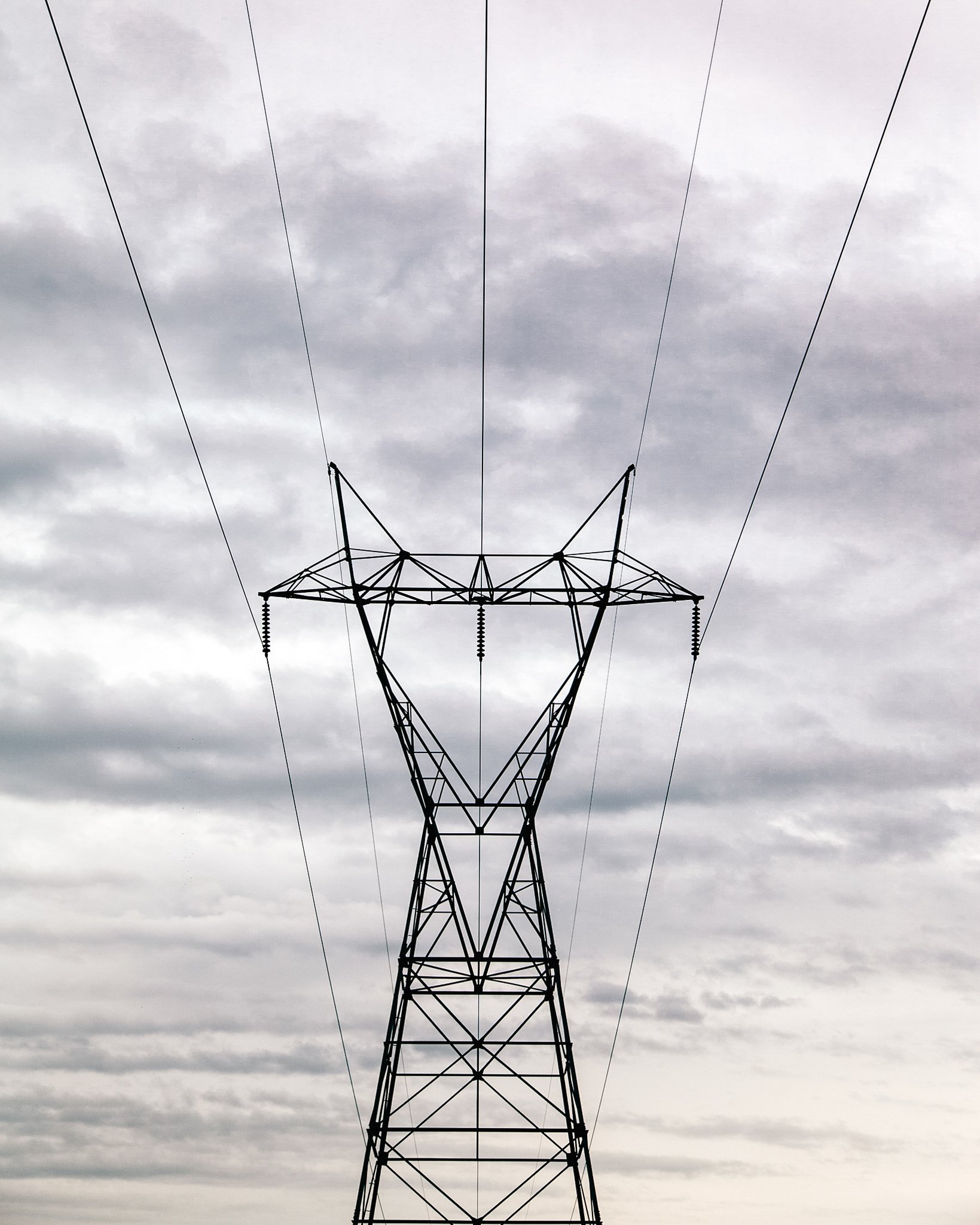Electric power line tower against a cloudy sky.
