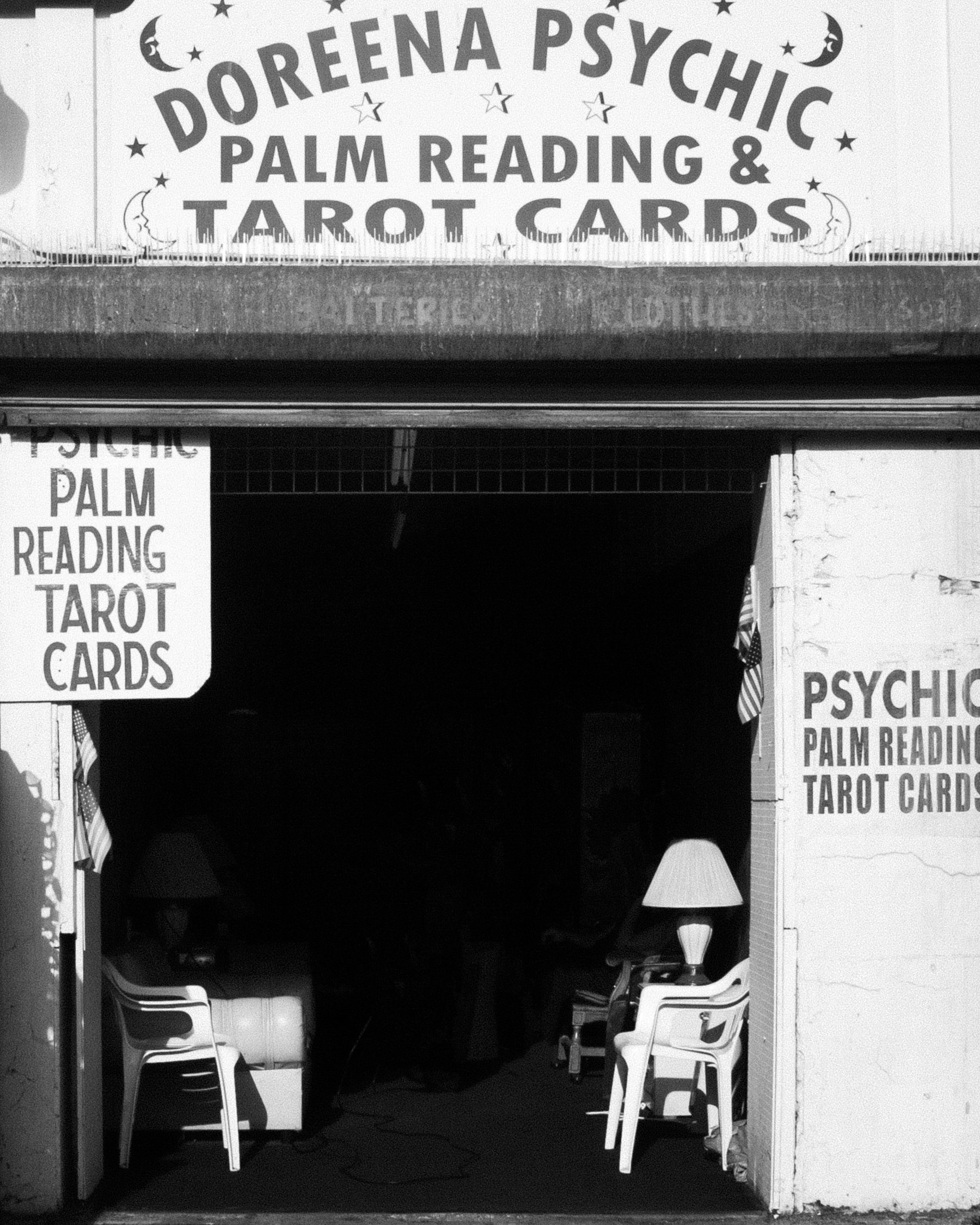 Storefront advertising psychic services, palm reading, and tarot cards. Display includes signs with text, chairs inside, and a decorative lamp.