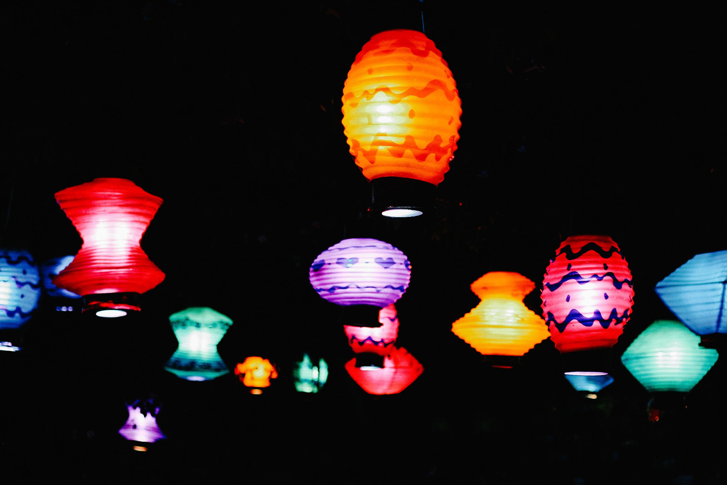 Colorful paper lanterns hanging against a dark night sky.