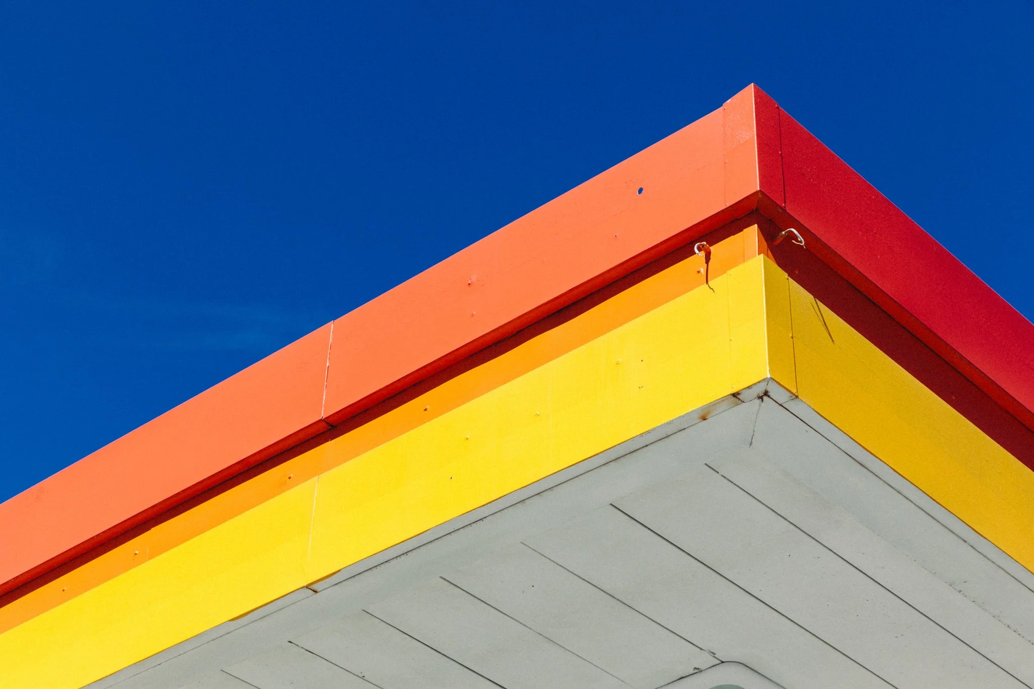 Close-up of a corner of a building painted in bright colors with a deep blue sky in the background.