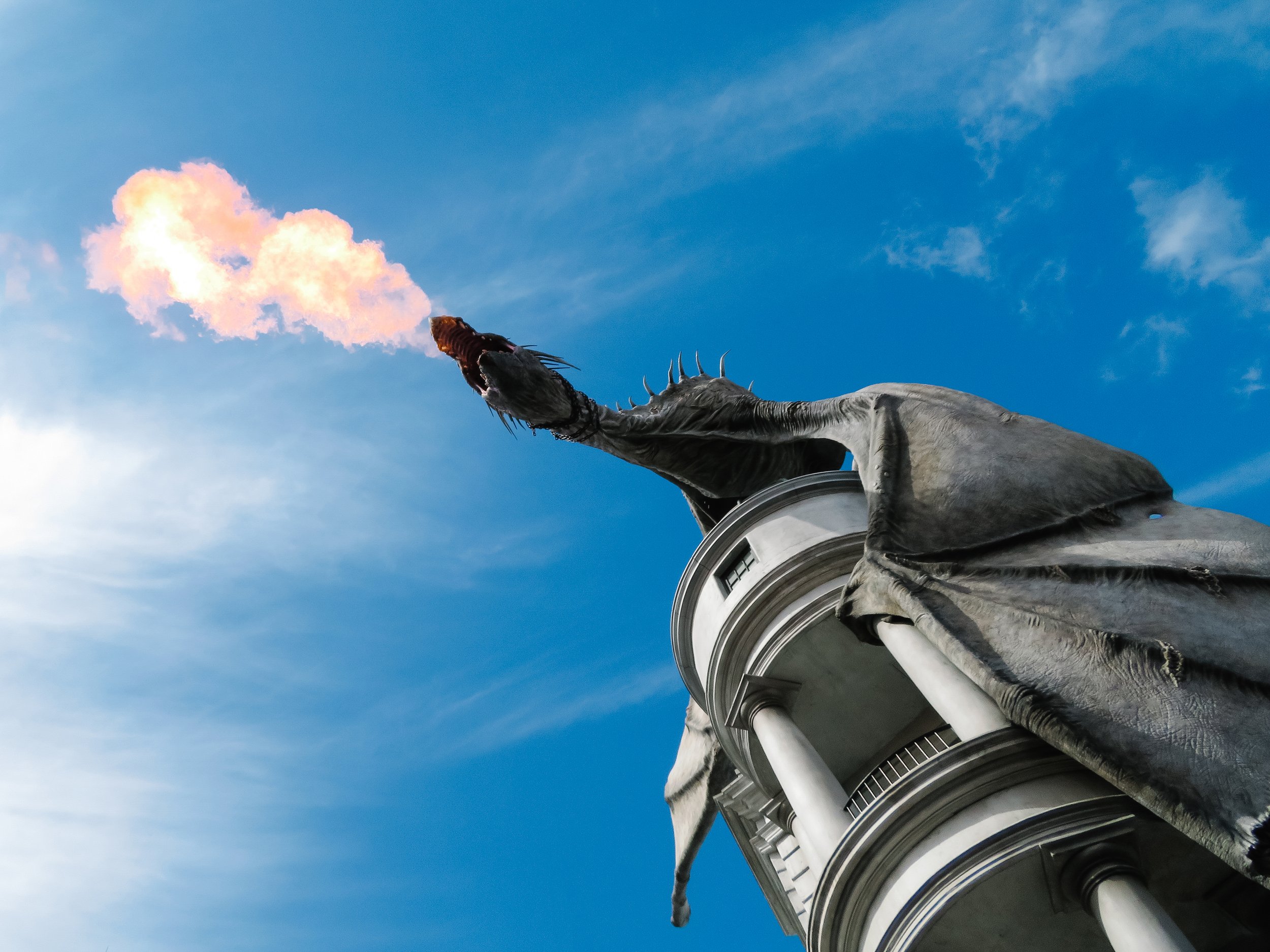 A close-up view of the Statue of Liberty's torch against a blue sky with scattered clouds.