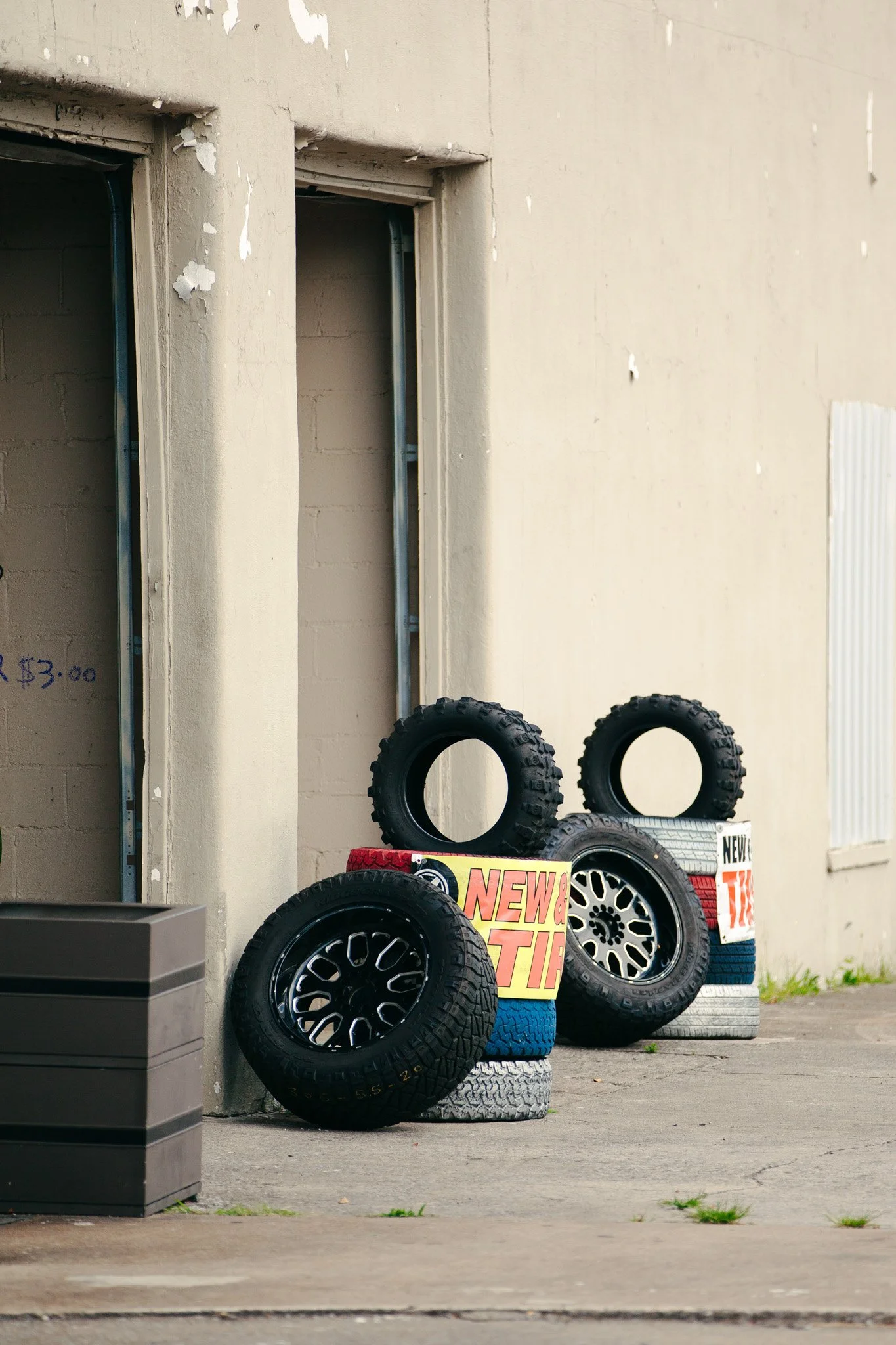 Display of various tires at an auto parts store, with some tires stacked on top of each other and a promotional sign reading 'NEW & TIGHT'.