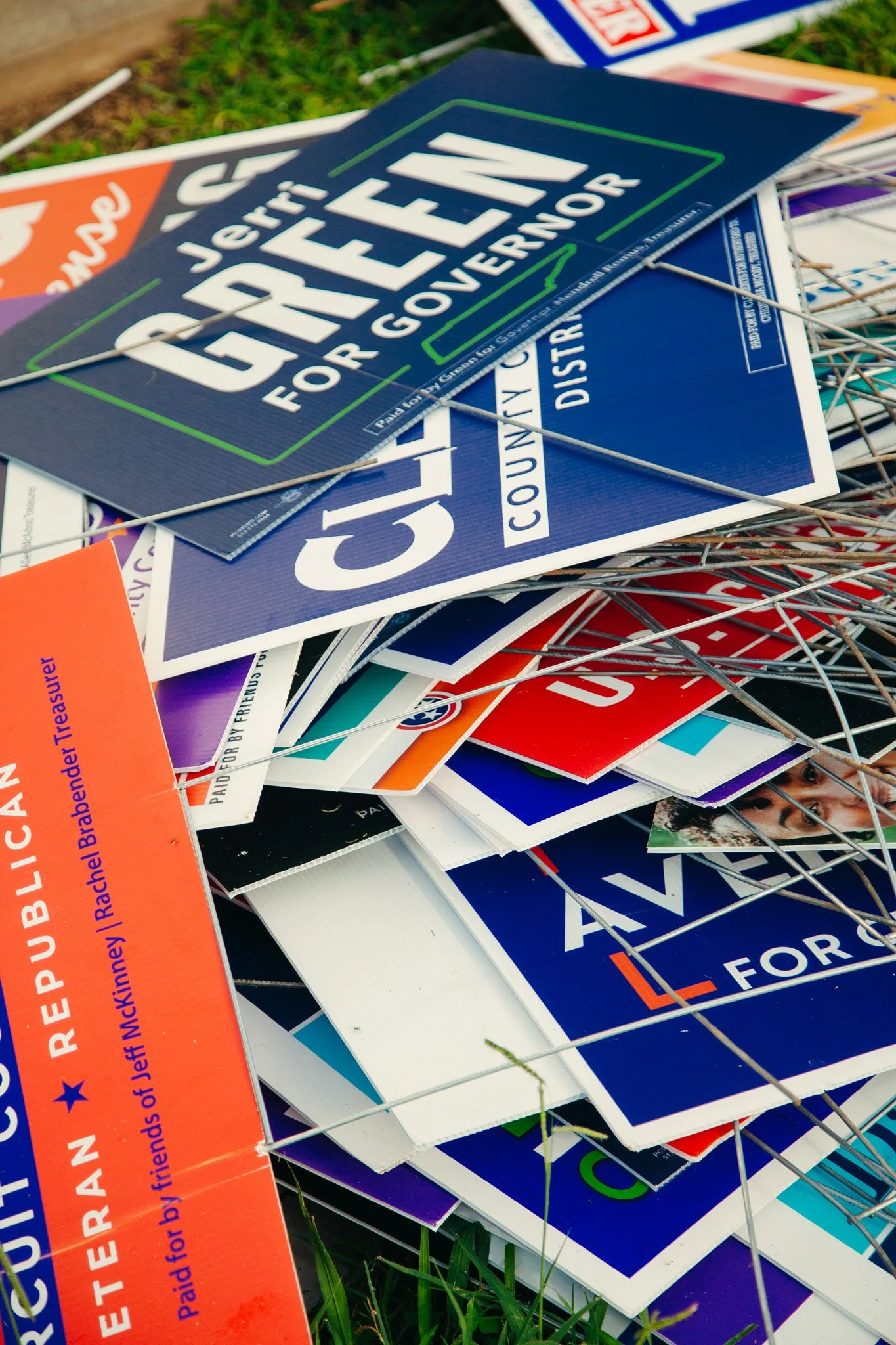 Pile of political campaign signs on grass, including signs for various candidates and issues, with some signs overlapping and wires visible in Murfreesboro, TN