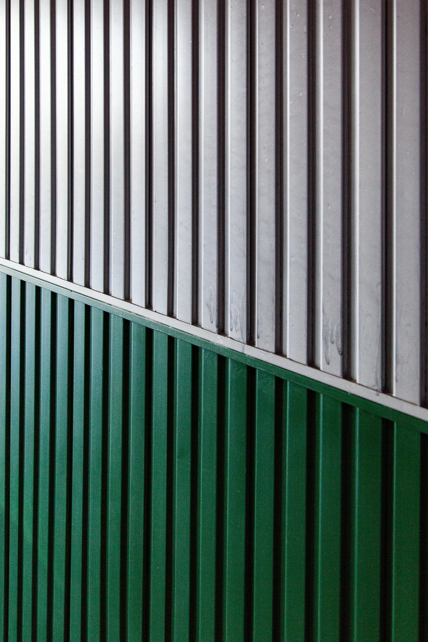 A physical wall with vertical metal bars painted white in the upper section and green in the lower section.