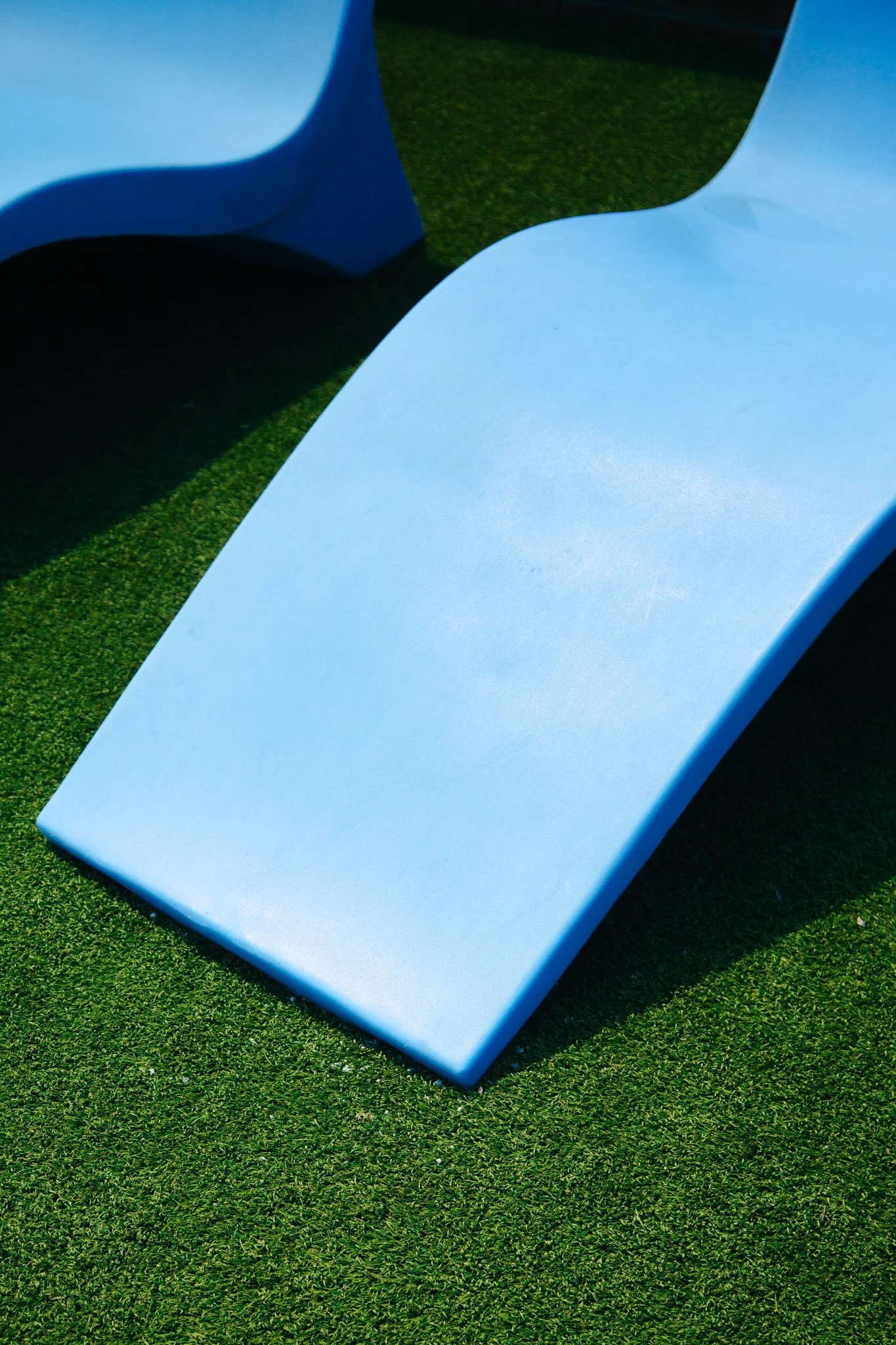 Close-up view of a light blue bench on green artificial turf at Tanger Outlets in Antioch, TN