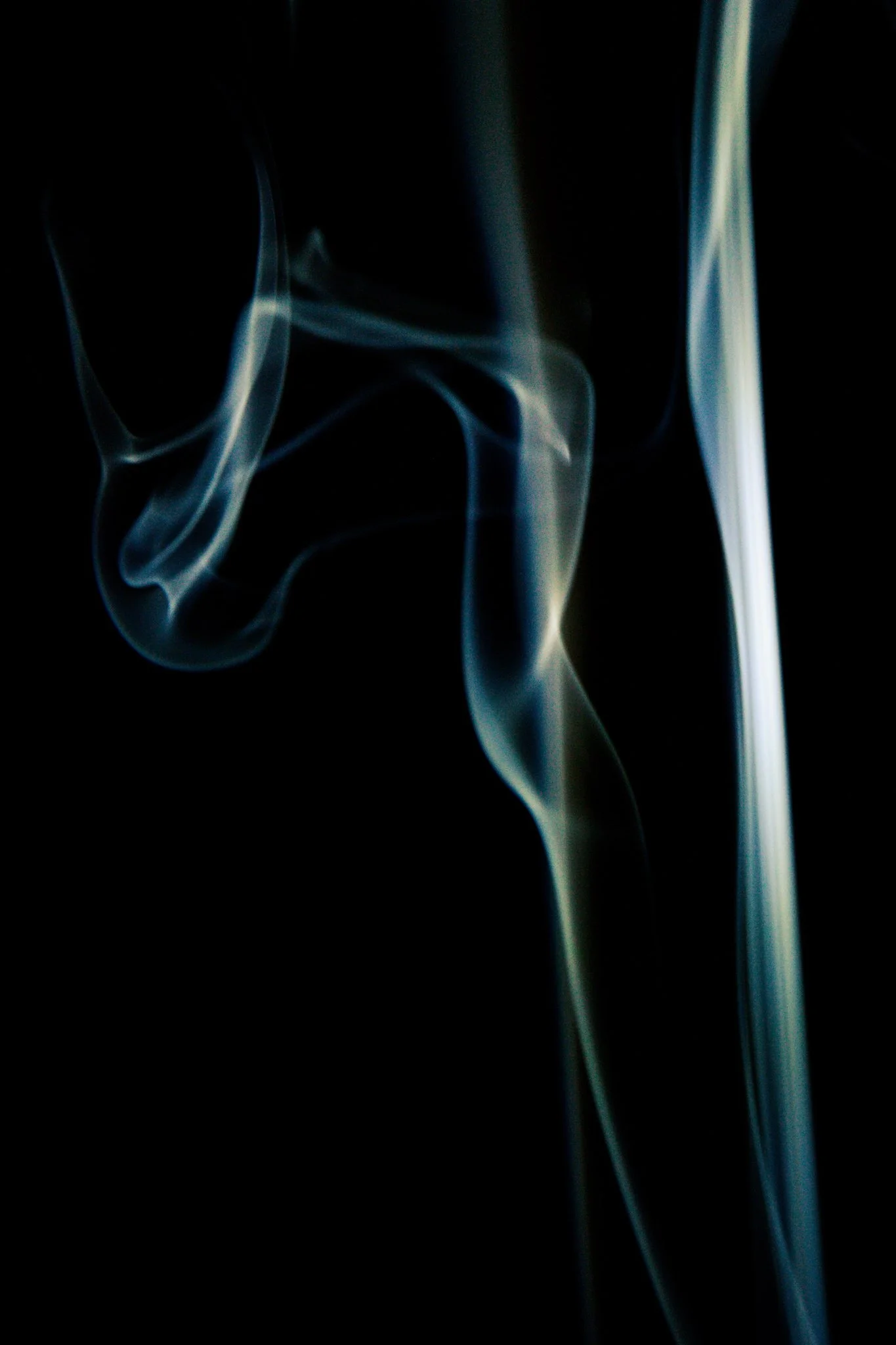 Thin wisps of smoke or vapor against a dark background, illuminated with a soft glow.