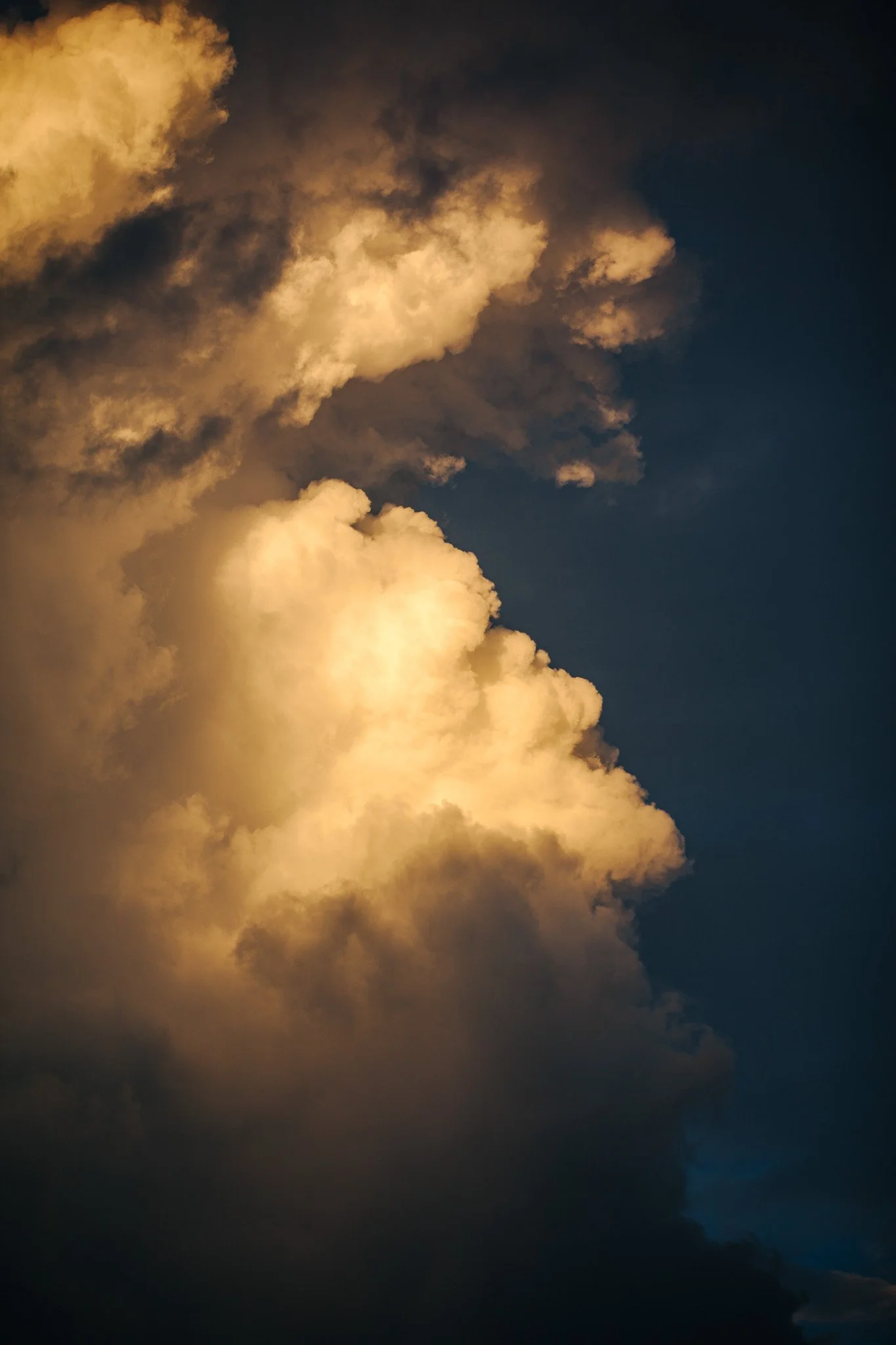 Clouds illuminated by sunlight against a dark evening sky.