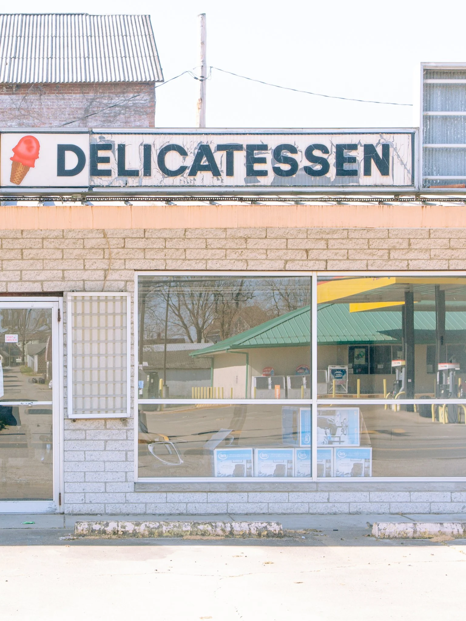 Storefront with a sign that reads 'DELICATESSEN' with a picture of an ice cream cone on the left.
