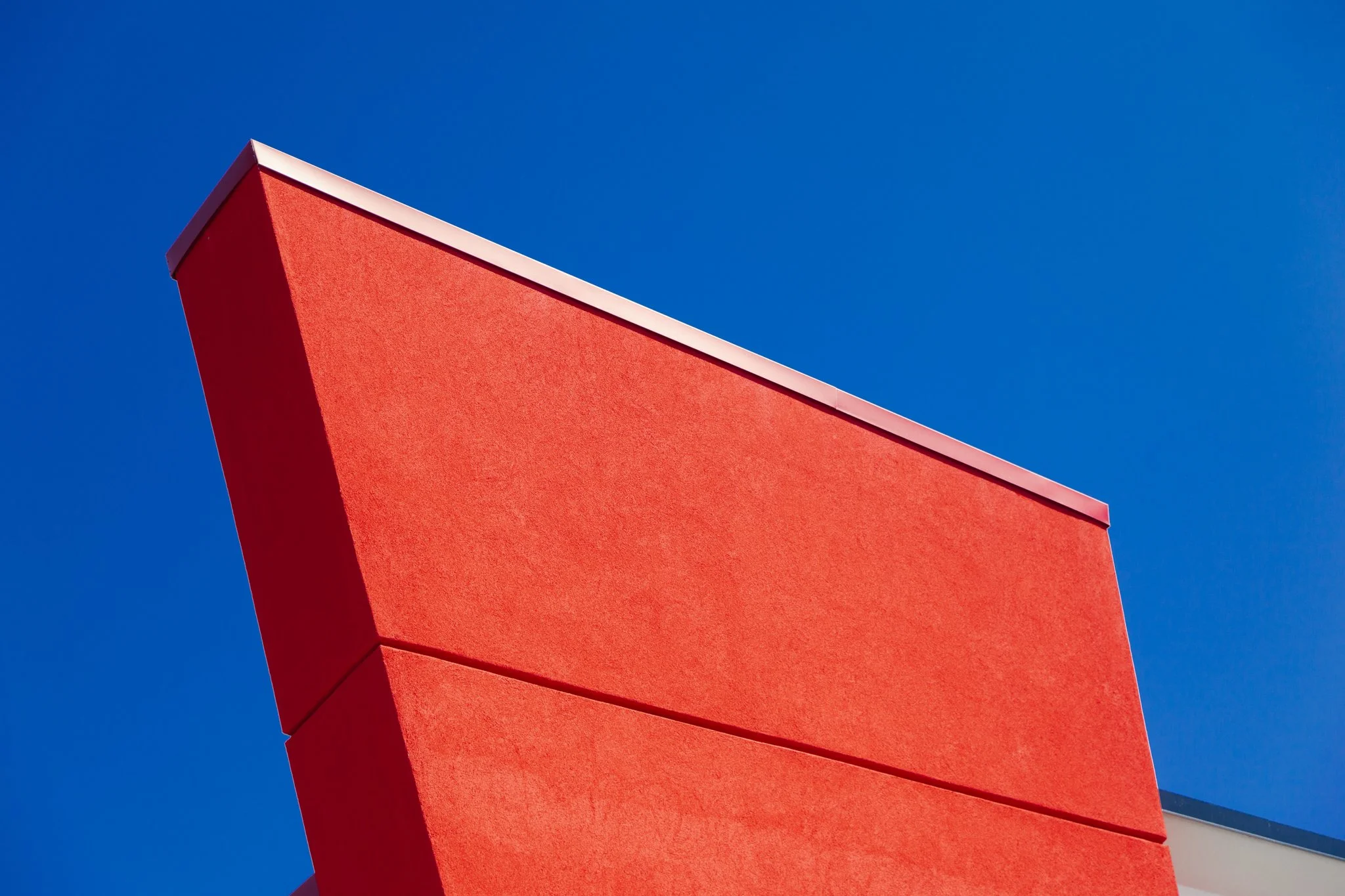 Close-up of a red architectural structure against a clear blue sky.