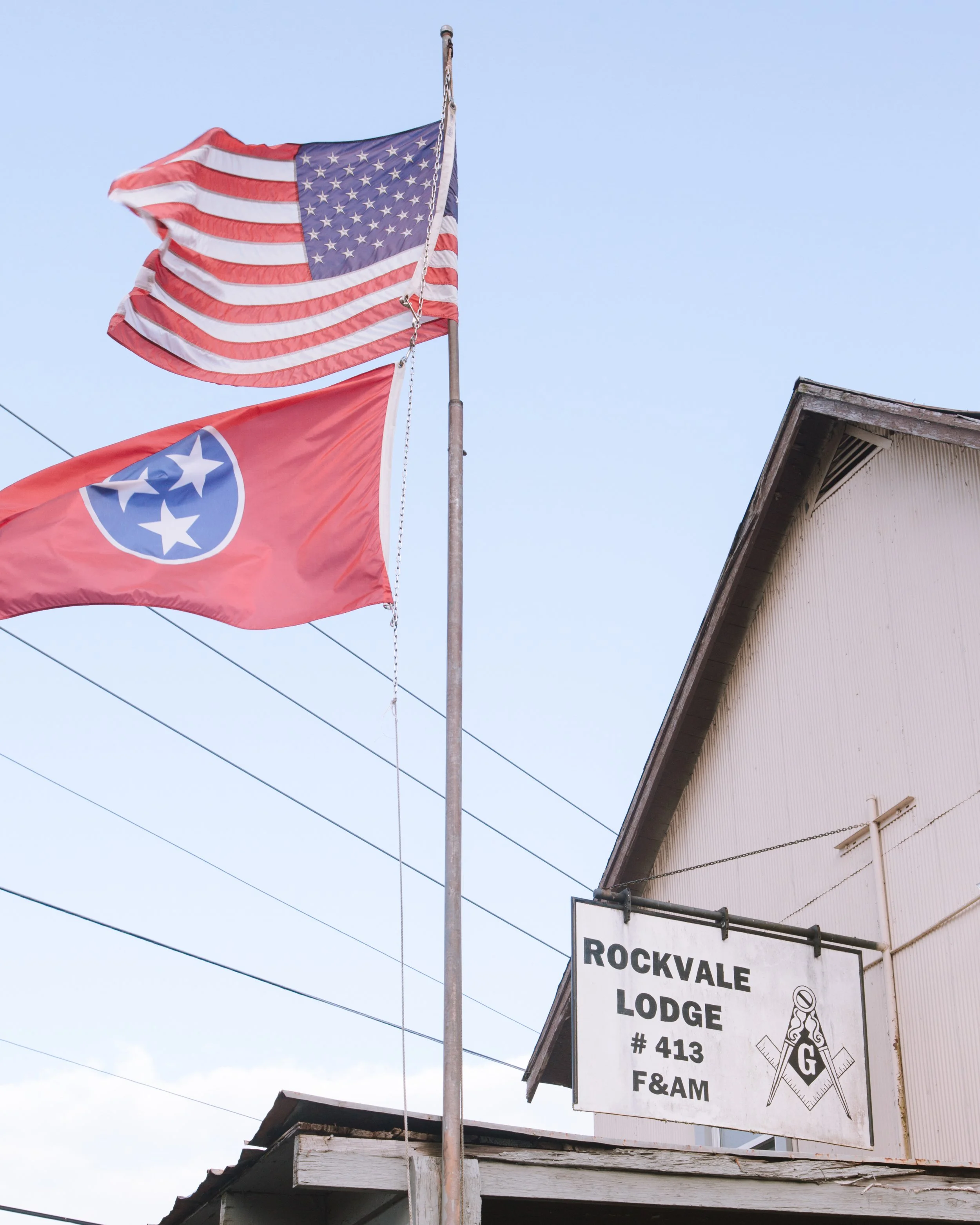 American flag and Tennessee state flag flying outside a building with a sign for Rockyvale Lodge #413 F&AM.
