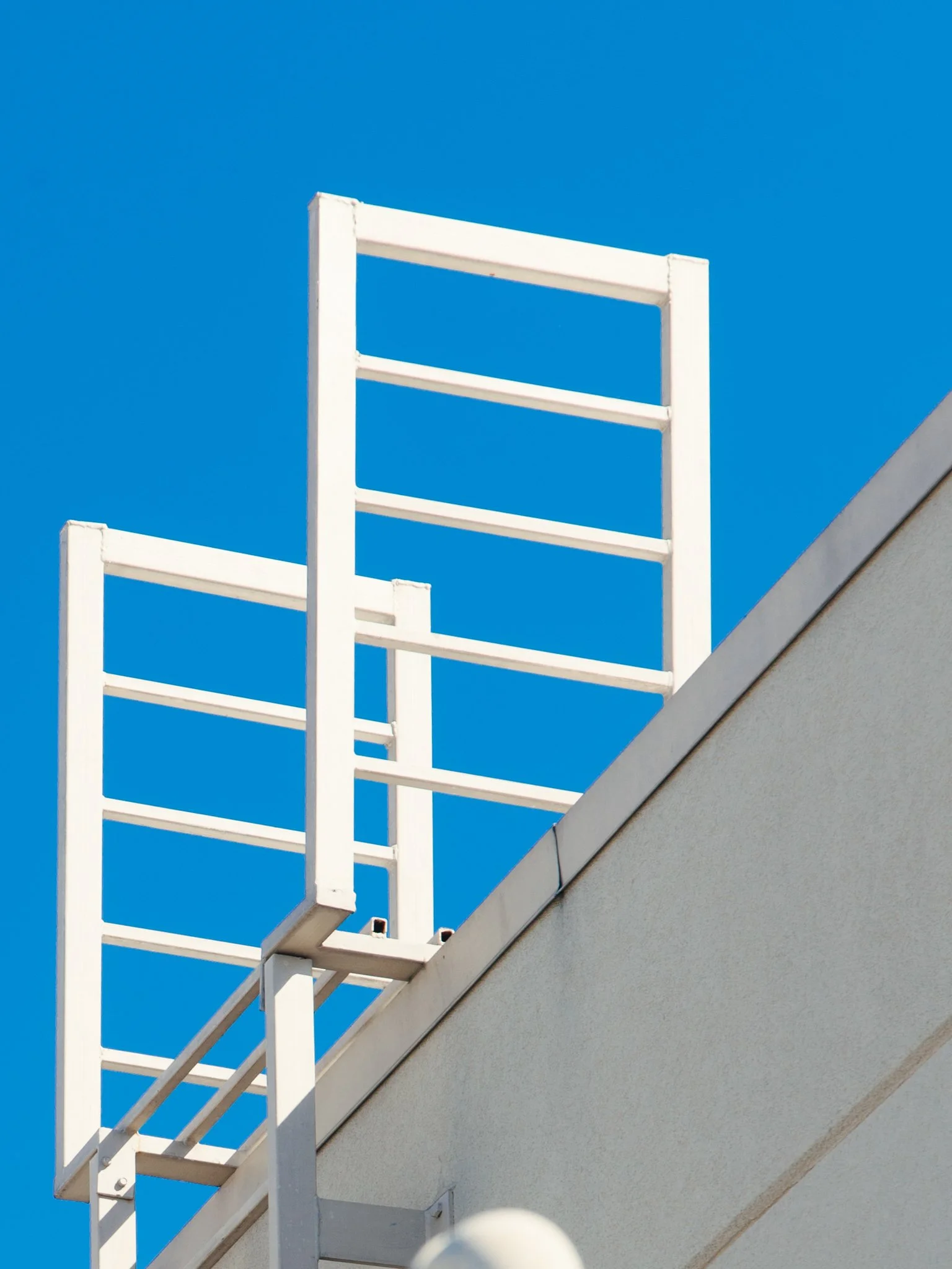 White wooden balcony railing on a residential building against a clear blue sky.