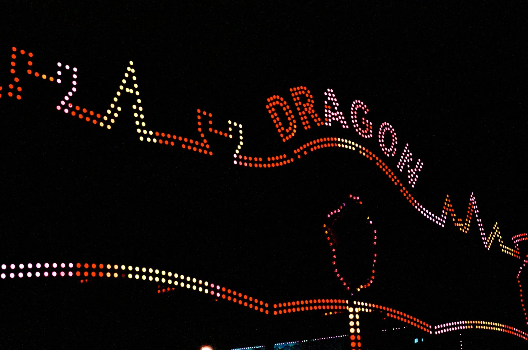 Colorful illuminated sign spelling out 'LAS VEGAS' in bright pink, orange, yellow, and purple dots against a dark night sky.