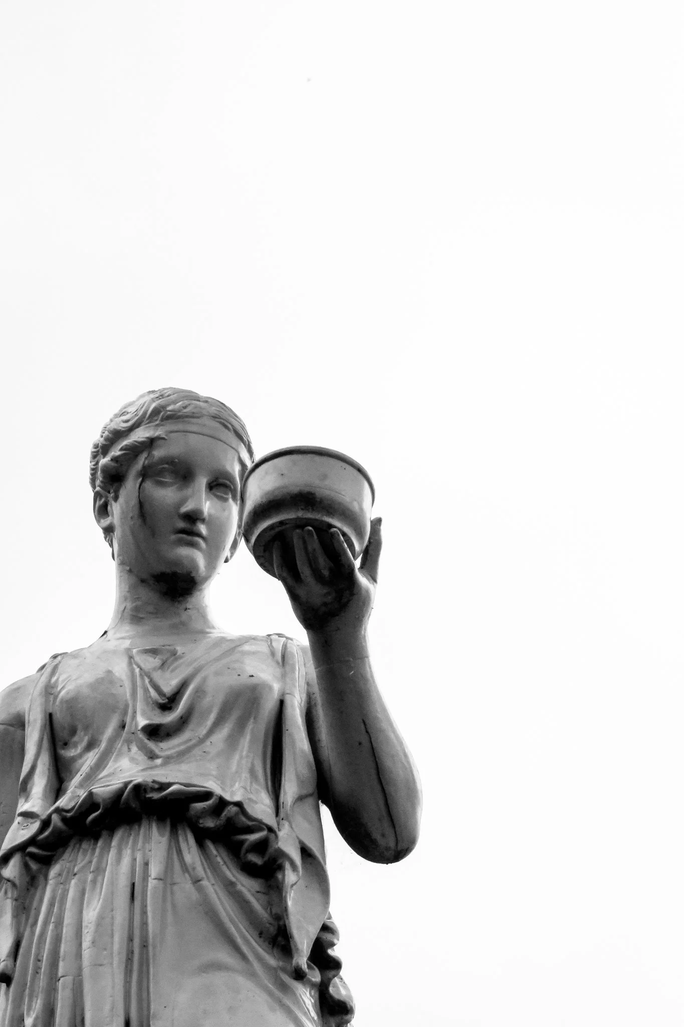 Black and white photo of the Statue of Liberty's face, upper body, and torch, seen from below against a plain sky.