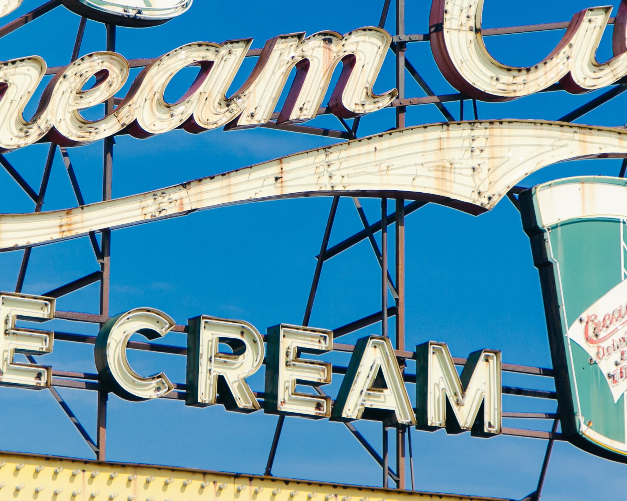 Close-up of a vintage neon sign with the words 'Restaurant' and 'Bar' against a blue sky.