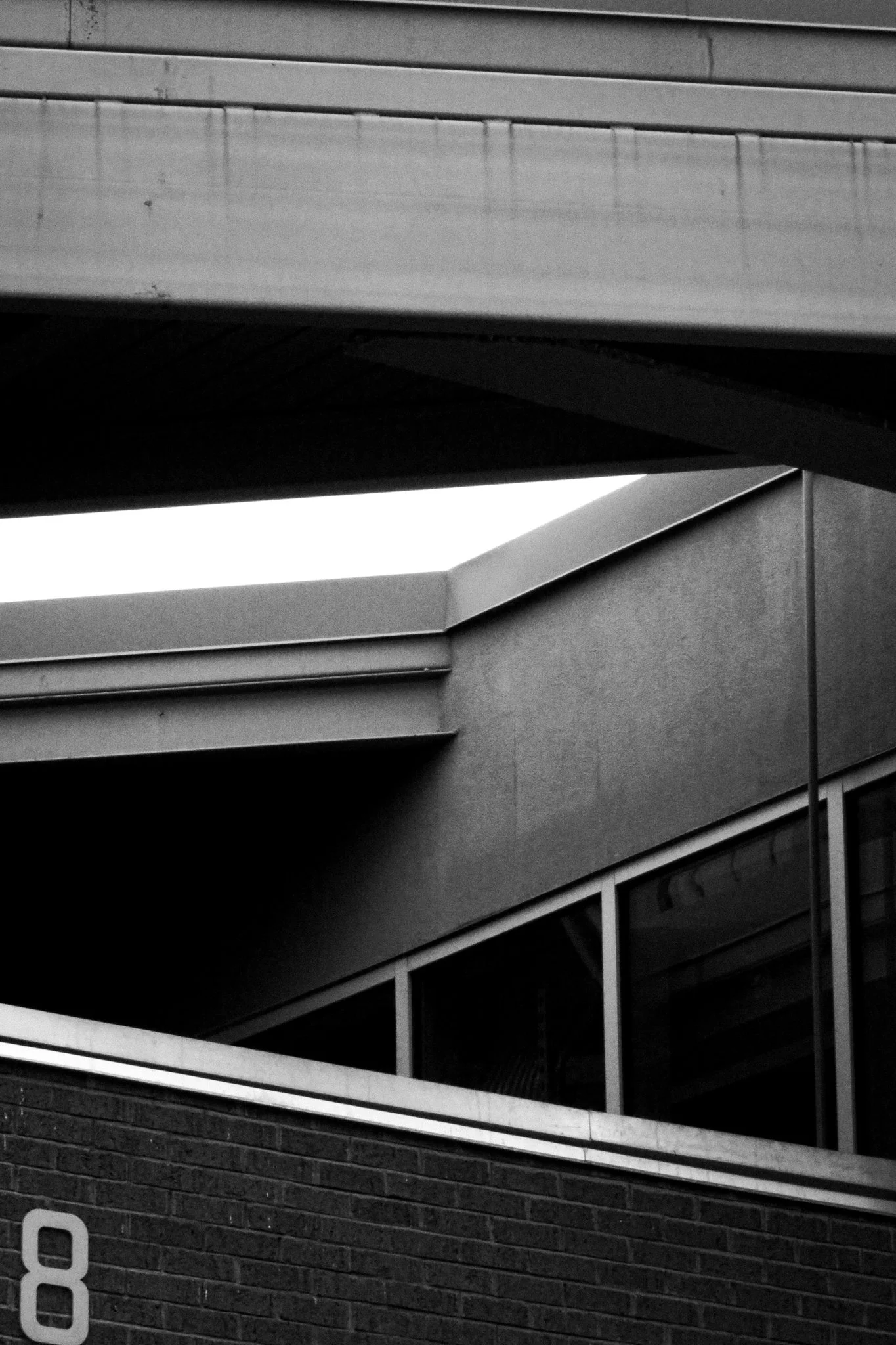 Black and white photo of a modern building with horizontal lines, brick wall, and glass windows.