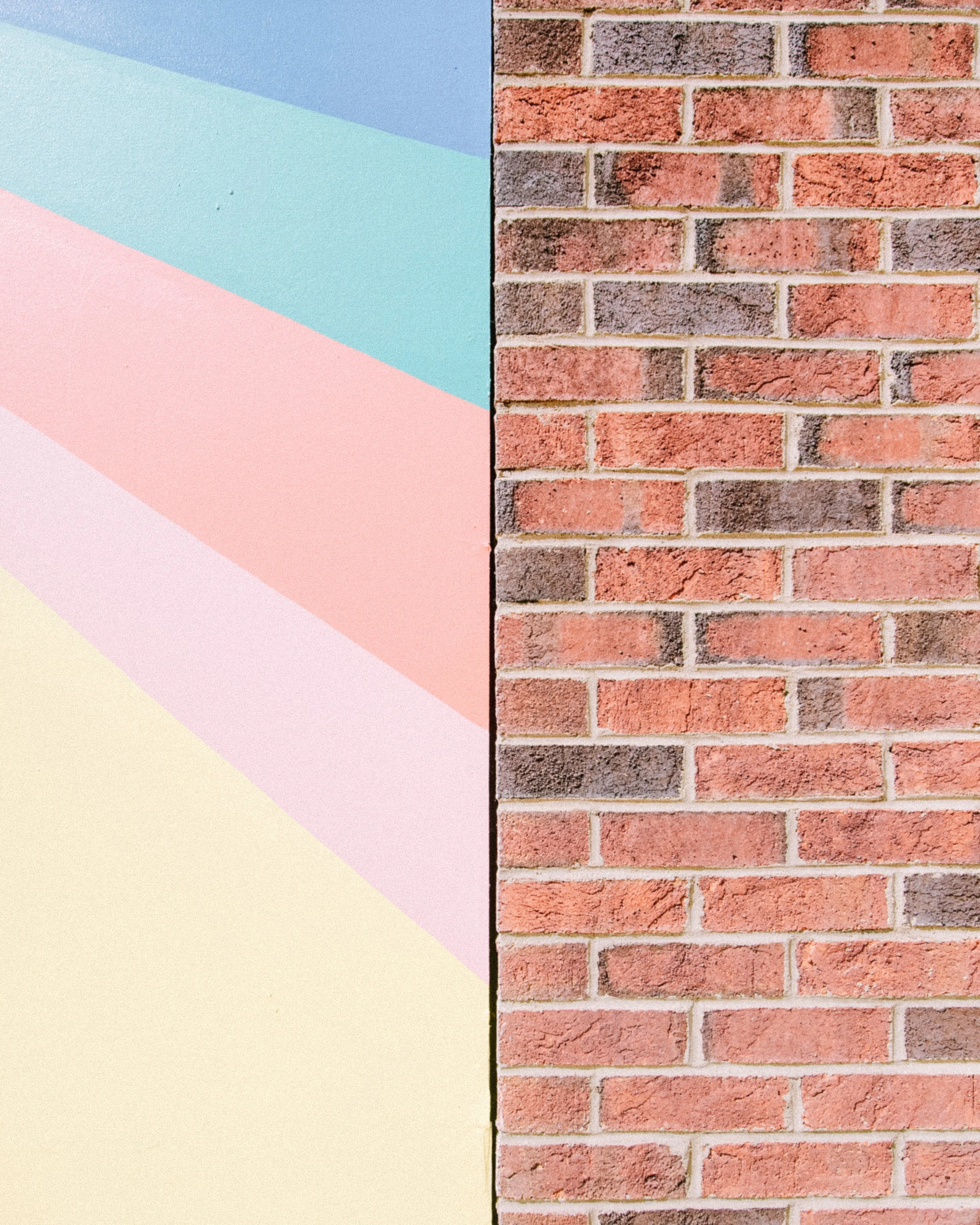 Side-by-side comparison of a brick wall with red bricks on the right and a painted wall with pastel geometric shapes on the left.