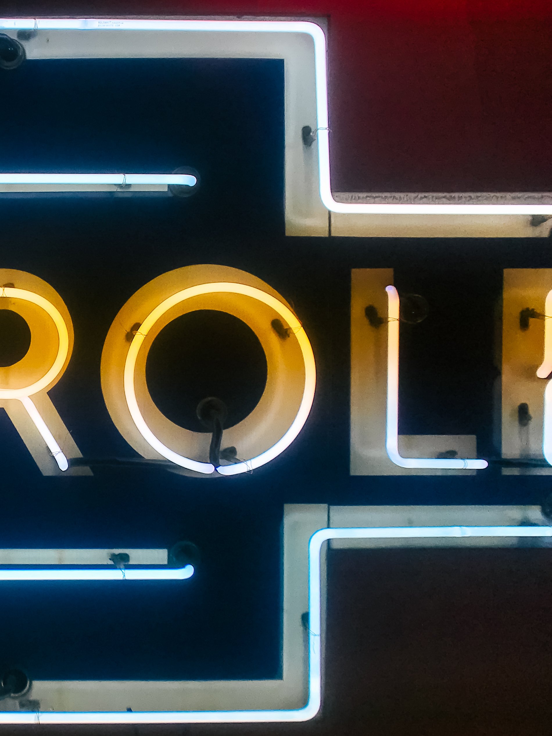Close-up of illuminated neon sign spelling the word 'LOVE' with yellow and white light tubes on a dark background.