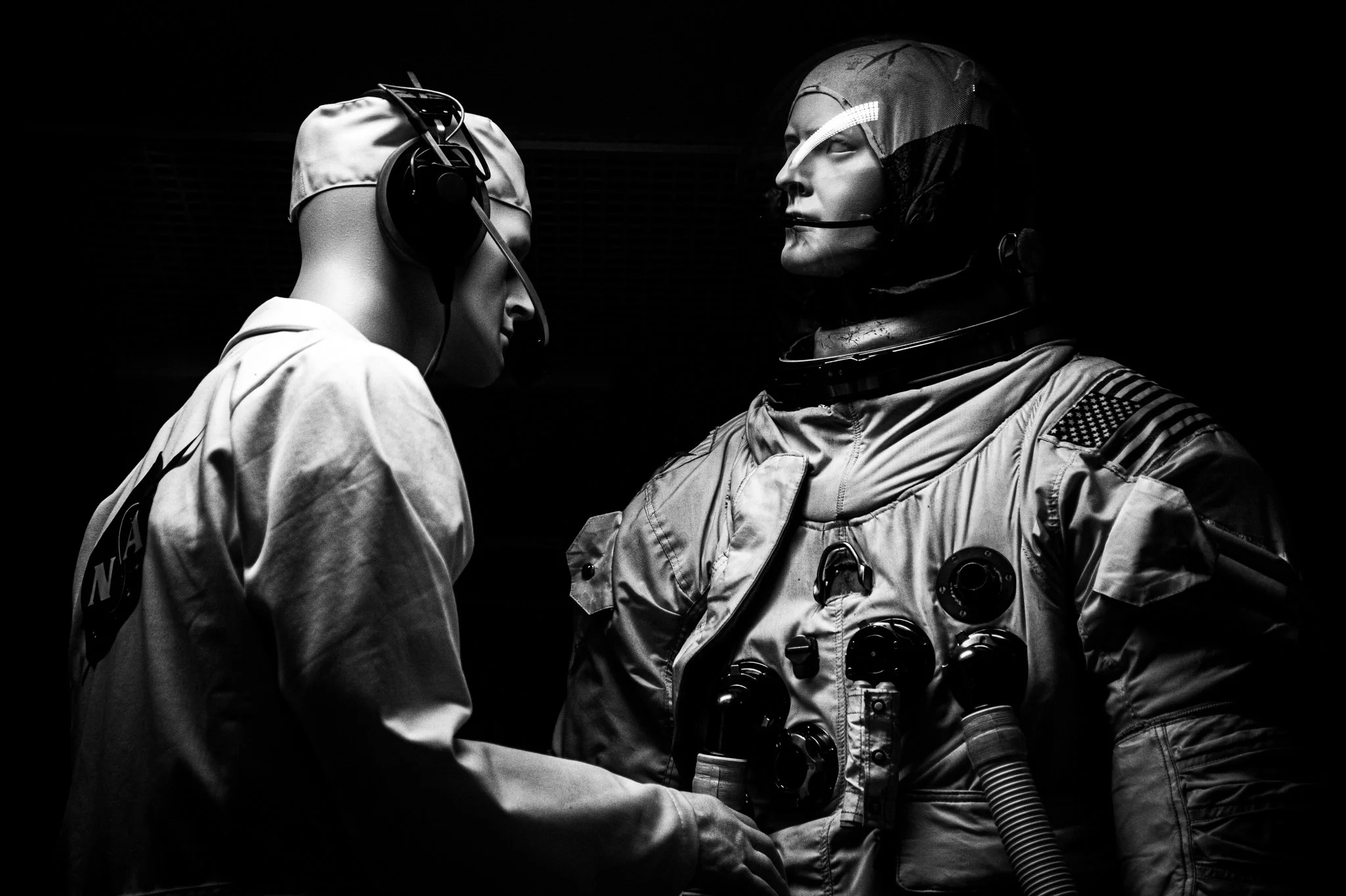 Two astronauts in space suits shaking hands, black and white photo.