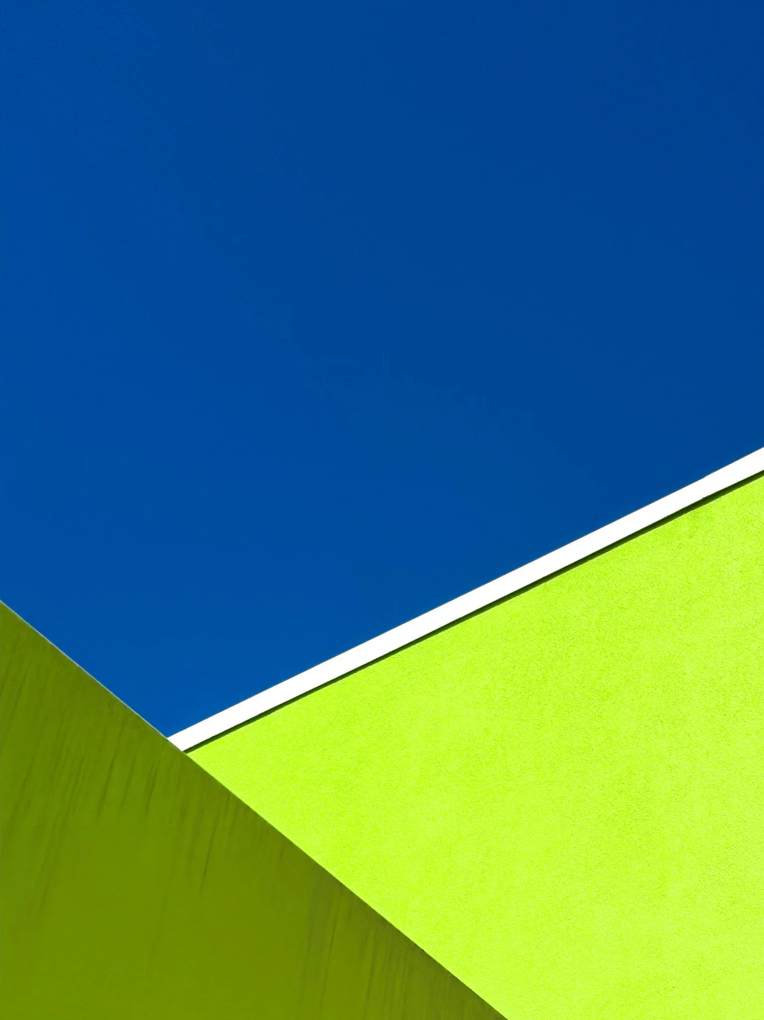Close-up of colorful paper sheets, blue and green, overlapping on a wooden surface.