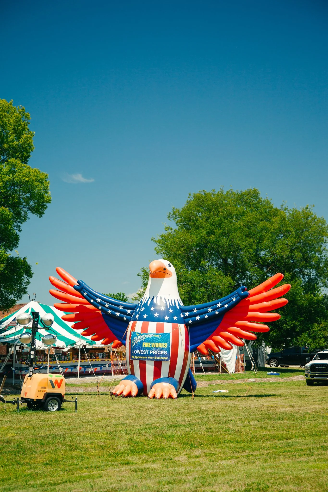 Colorful inflatable eagle at a fairgrounds with tents and a sign for fireworks.