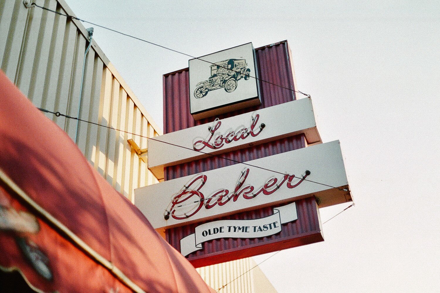 Vintage sign for Local Bakery with a drawing of an old car and text "Olde Tyme Taste".