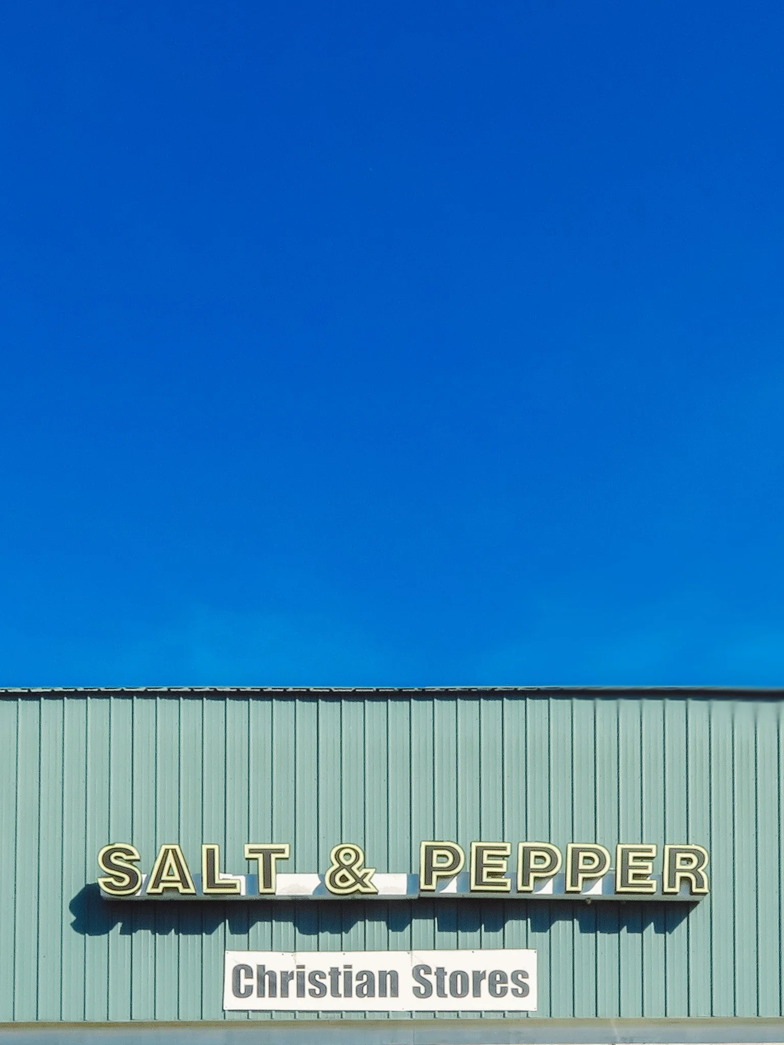 Sign on a green building with the words 'Salt & Pepper' in large letters and a smaller sign below reading 'Christian Stores'.