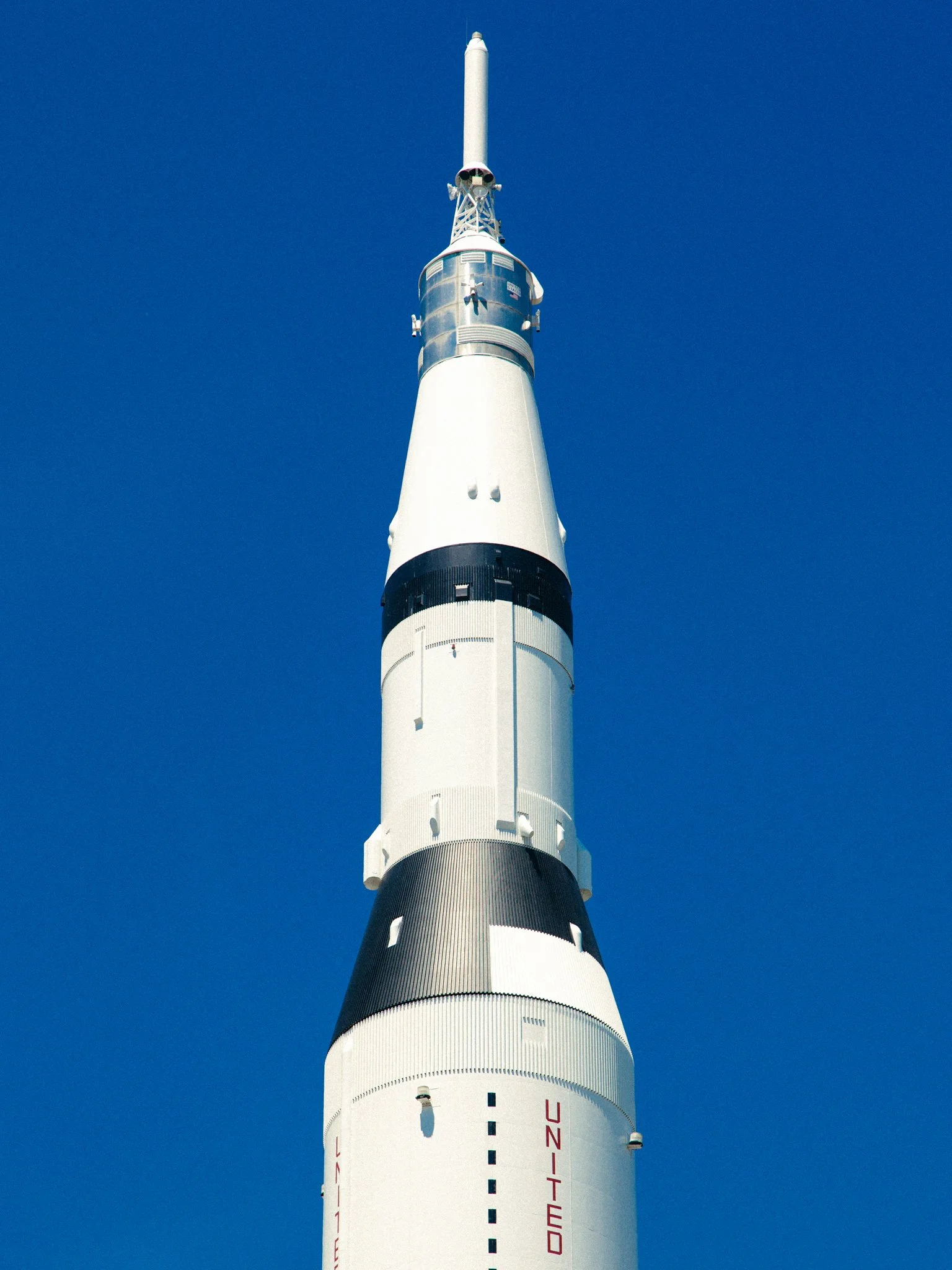 A tall SpaceX Falcon rocket standing vertically against a clear blue sky.