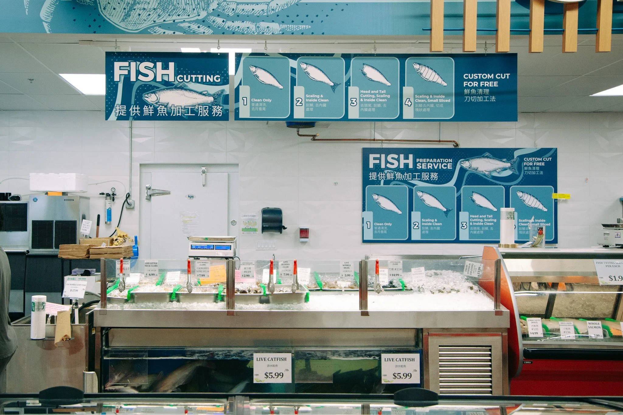 Display of various fresh fish on ice at a seafood market counter with signs indicating different types and prices, and instructional signage for fish cutting services in the background at Pan-Asia Supermarket in Antioch, TN