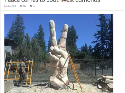 Large sculpture of a hand making a peace sign, carved with a chainsaw out of a tree stump by wood sculptor Tomas Vrba of Whatcom County Washington.