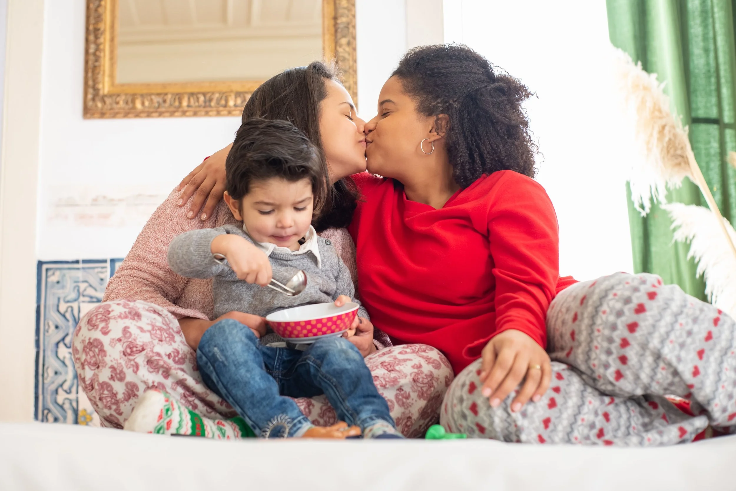 two moms kissing while holding their son