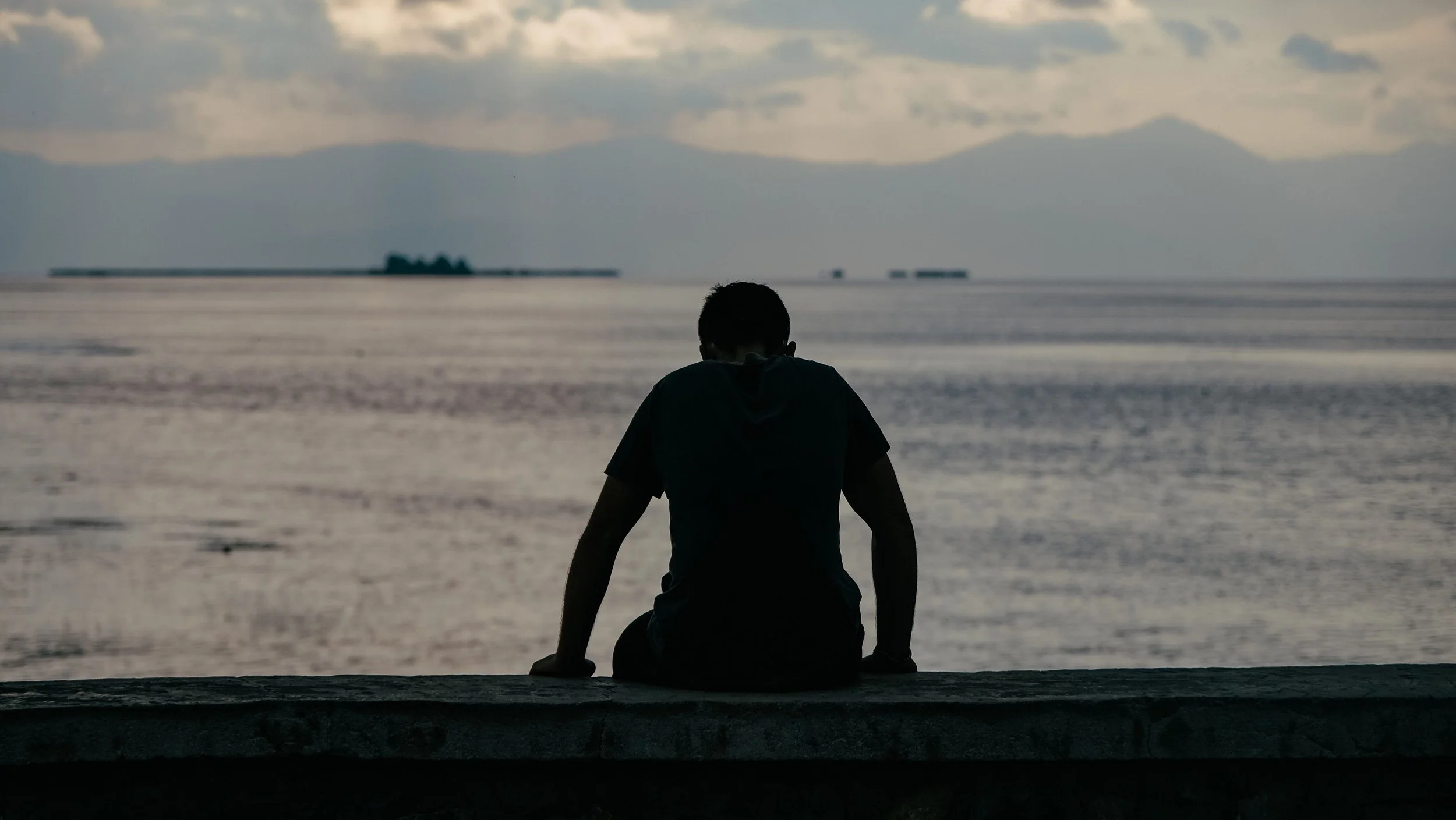 man sitting by lake