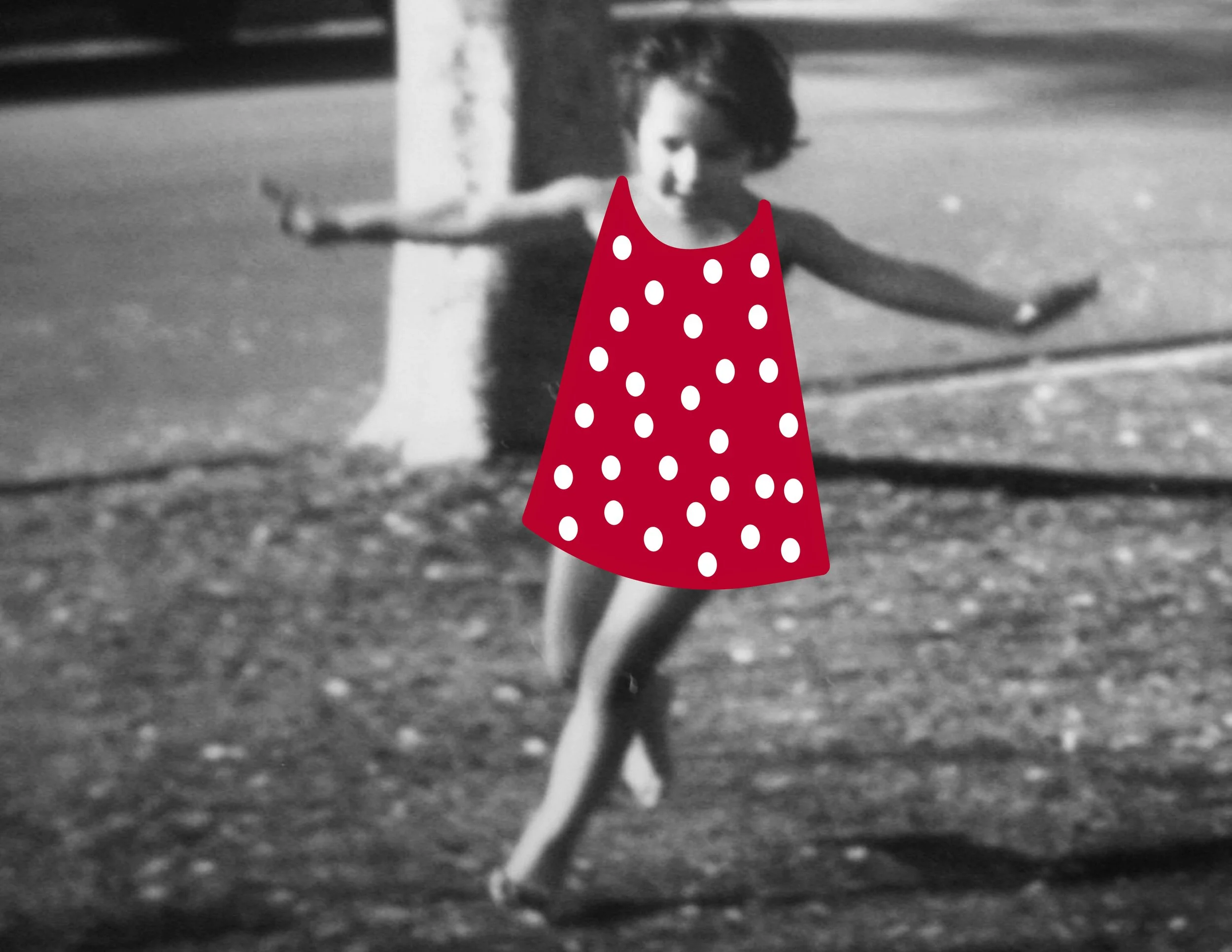 A young girl wearing a red dress with white polka dots, standing outdoors, with her arms extended to the sides.