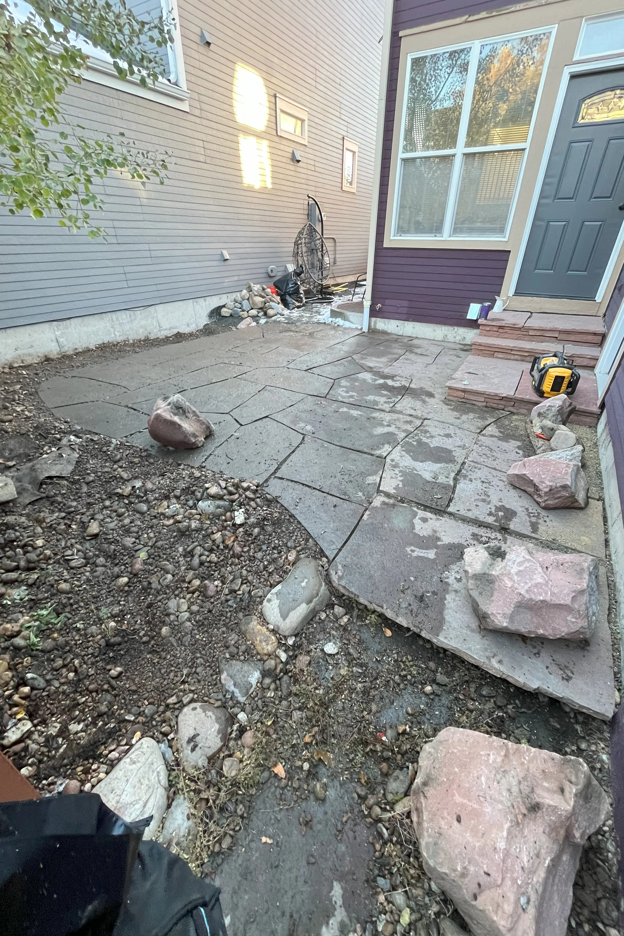 Flagstone Makeover: Weed Barrier and River Stone

We took on the task of revamping the space by adding a weed barrier, installing artificial turf along the side of the house, and replacing the existing rock with 2 tons of fresh, high-quality 3/4" riv