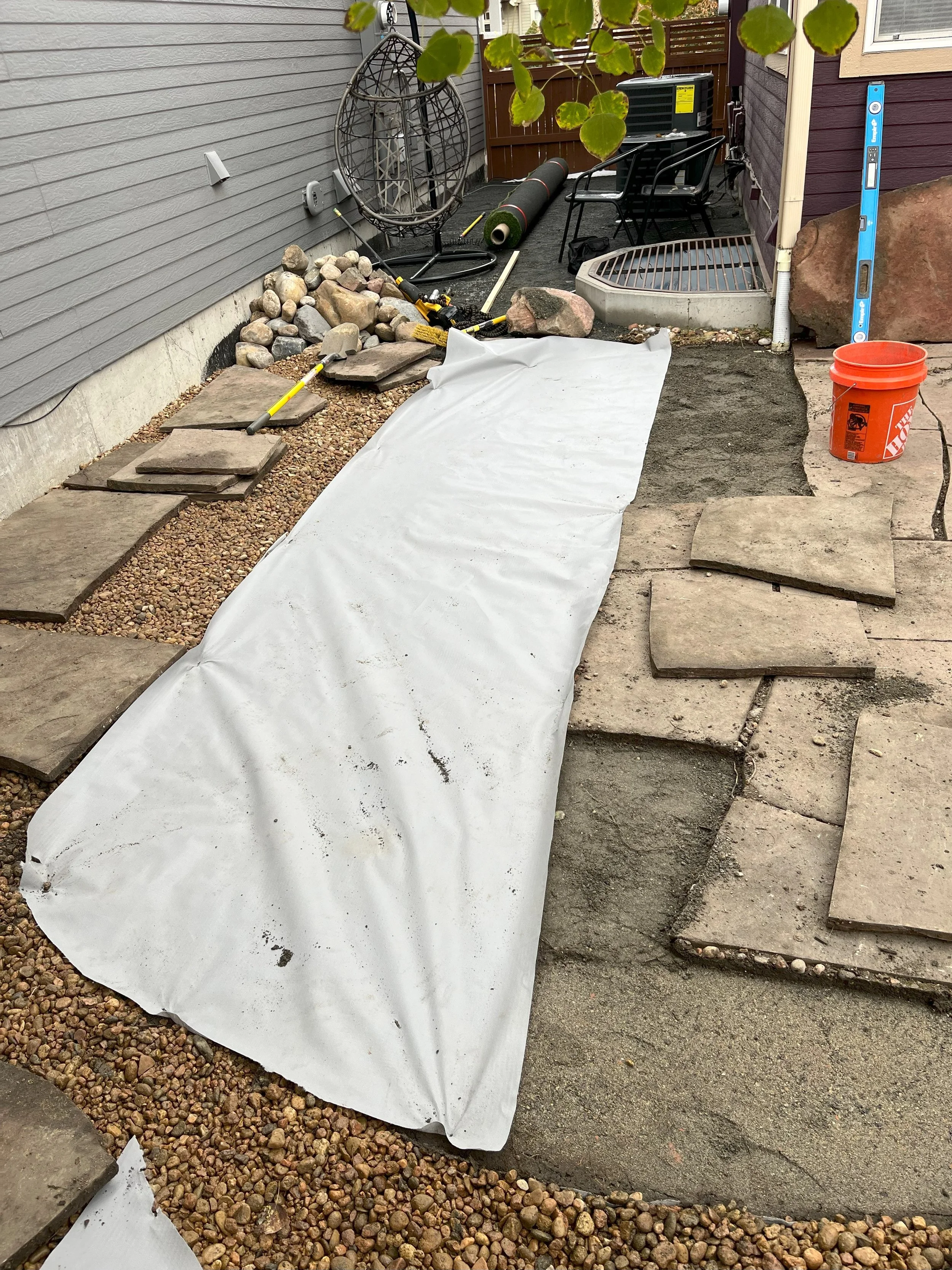 Flagstone Makeover: Weed Barrier and River Stone

We took on the task of revamping the space by adding a weed barrier, installing artificial turf along the side of the house, and replacing the existing rock with 2 tons of fresh, high-quality 3/4" riv