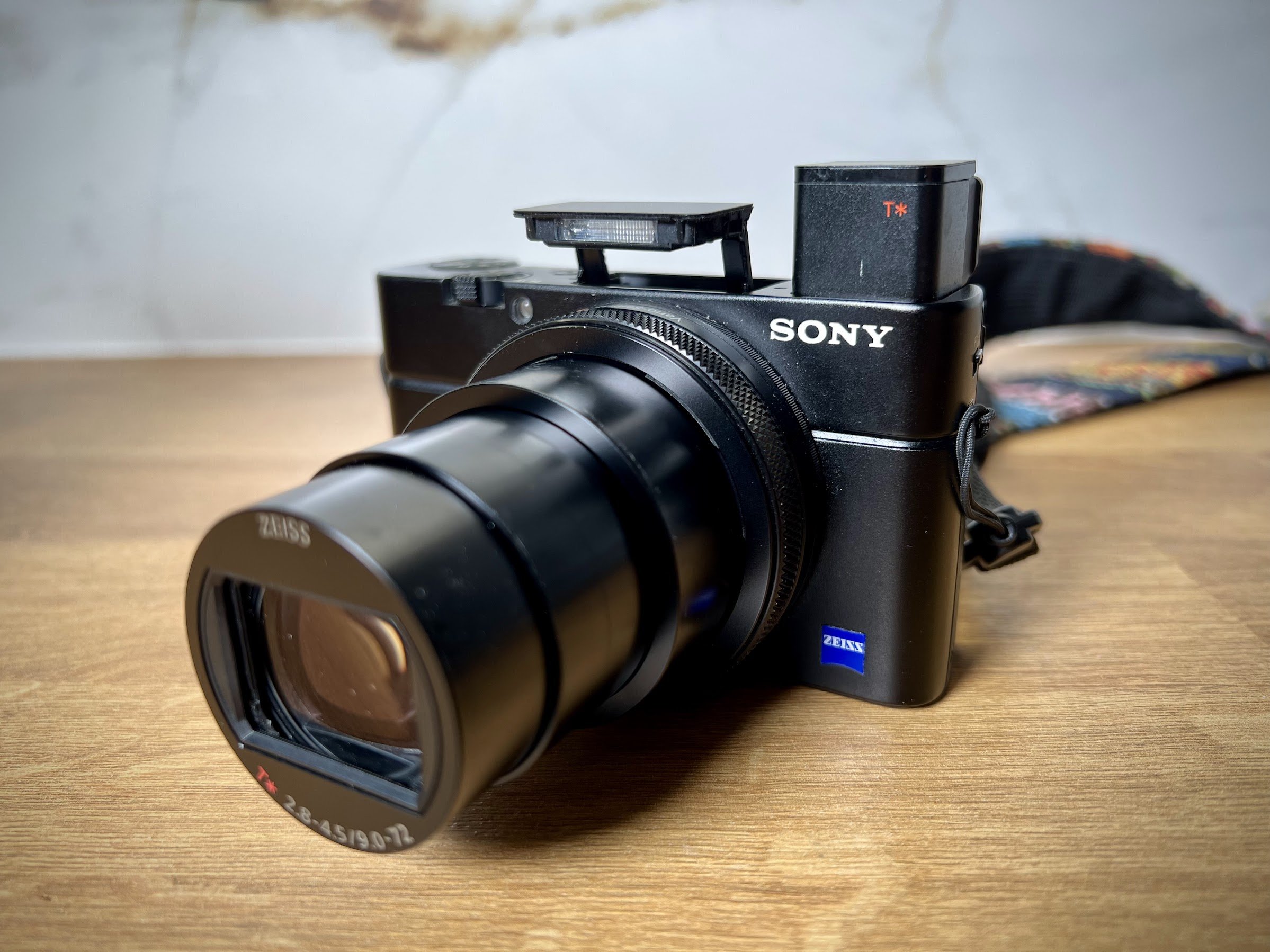 Close-up of a Sony compact camera with a Zeiss zoom lens on a wooden table