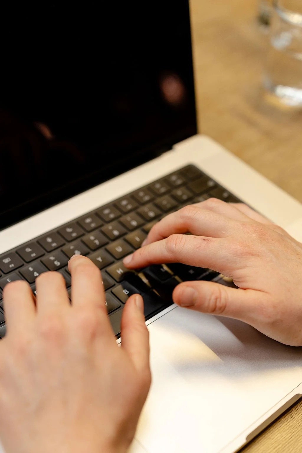 Hands typing on a black computer keyboard.
