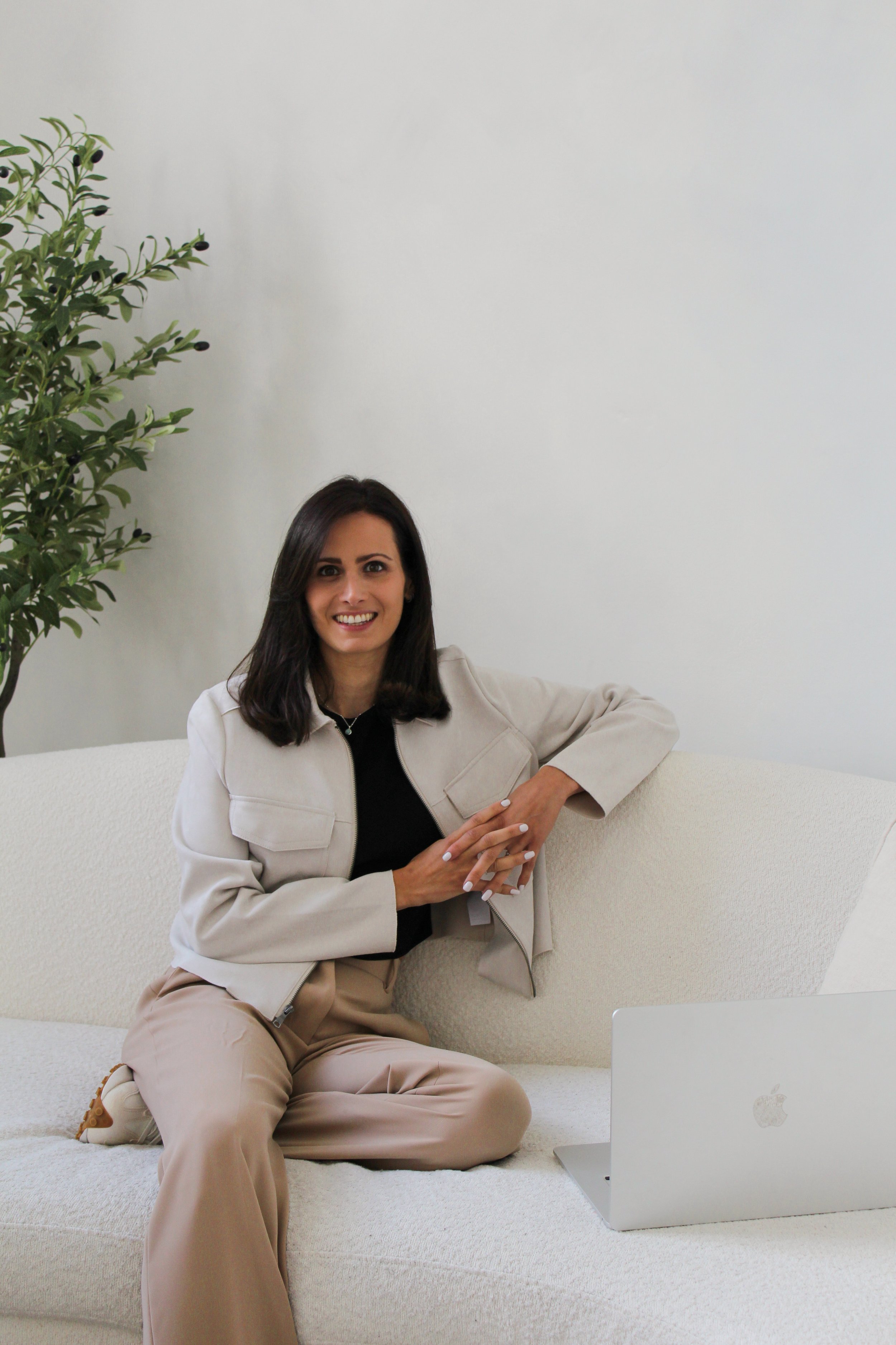 Photo of Shaady Harrison sitting on a sofa with a laptop in front of her.