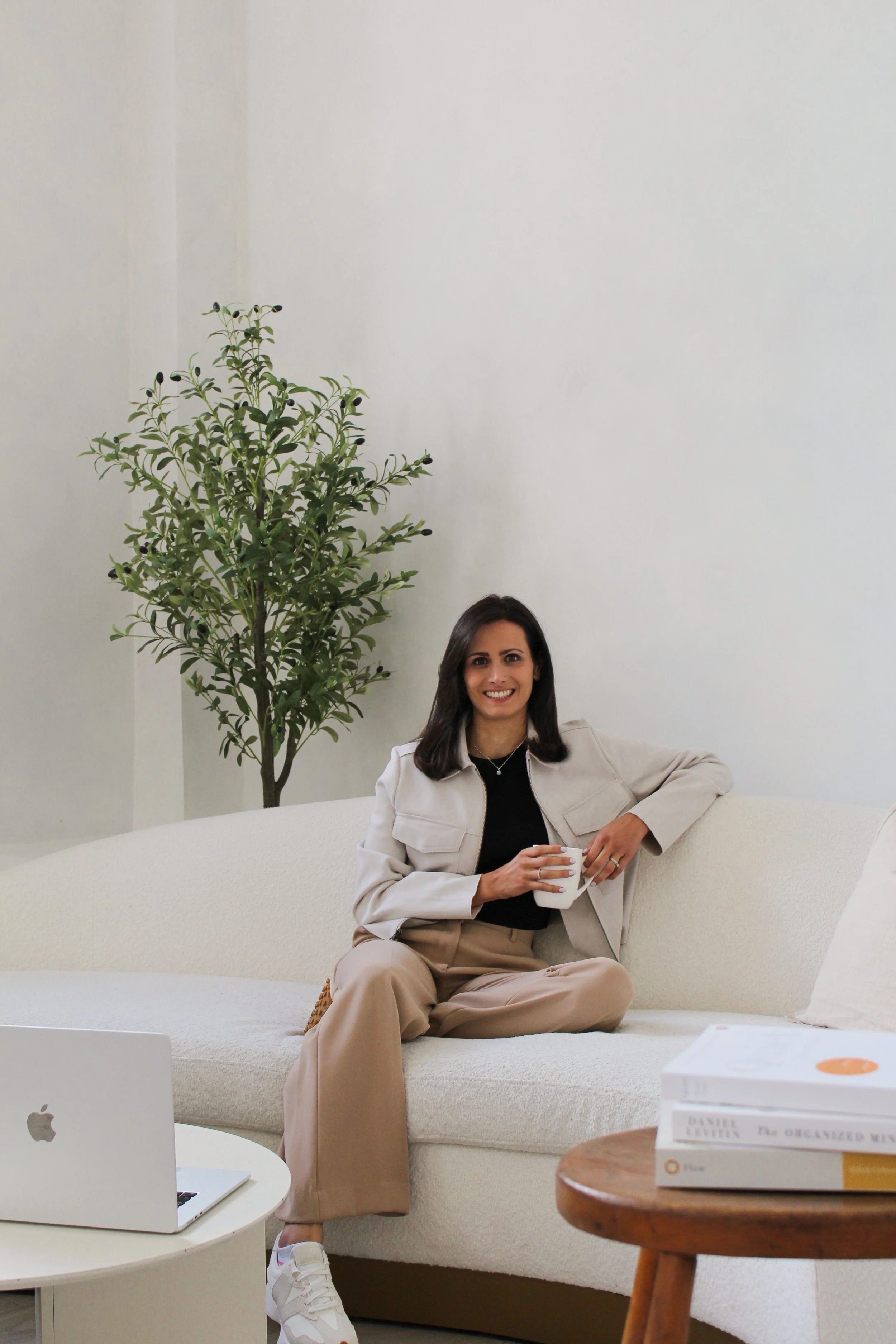 Photo of Shaady Harrison sitting on a sofa holding a cup of tea.