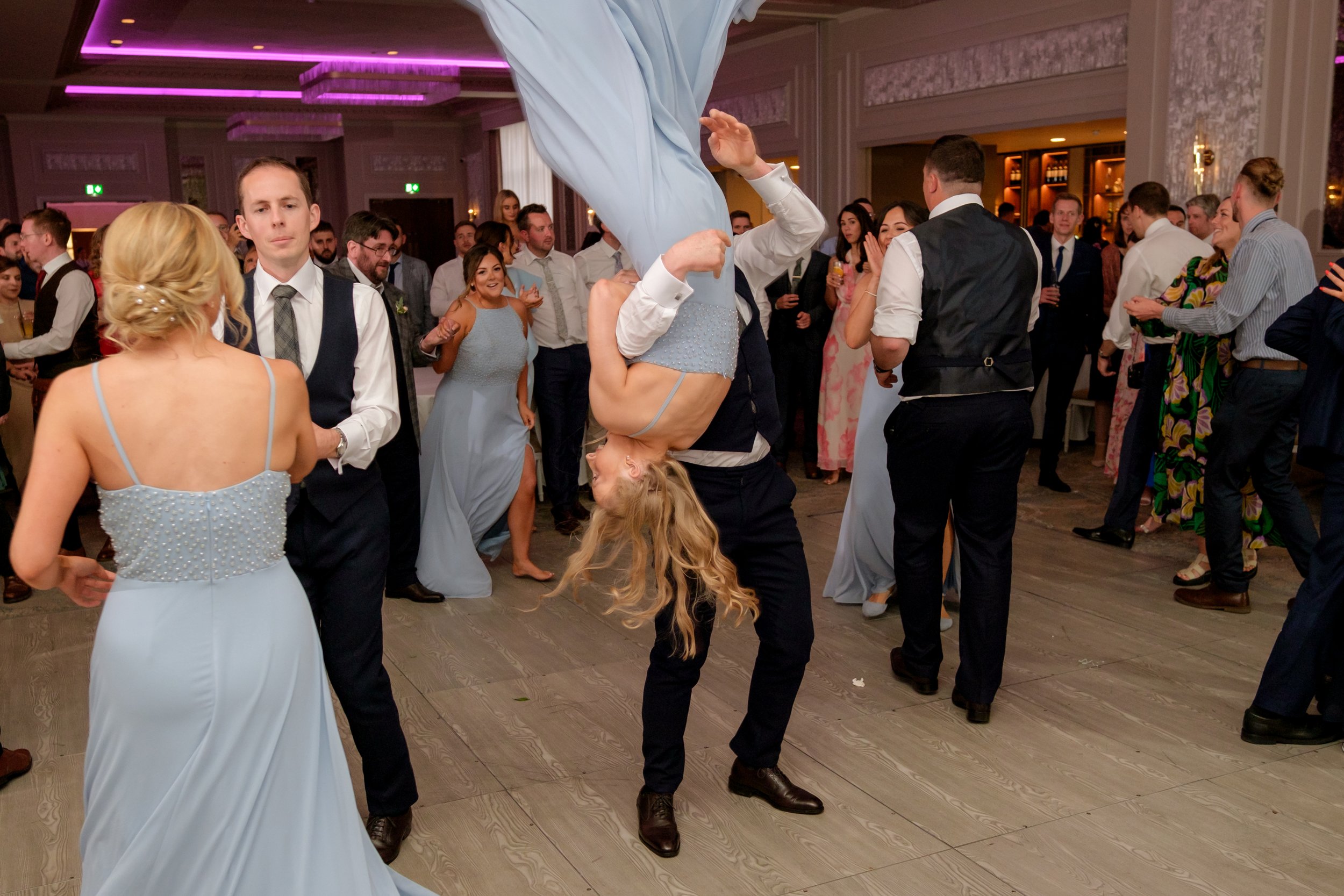 People dancing at a wedding reception, with a woman being lifted upside down while dancing.
