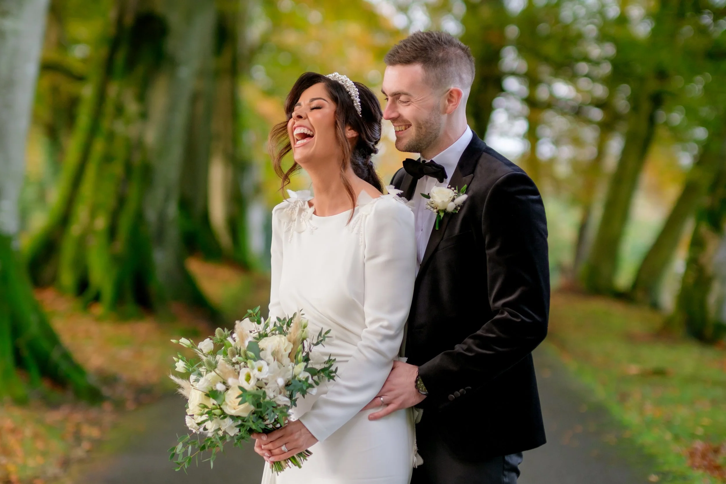 Bride and groom smiling and celebrating outdoors in a forest setting.
