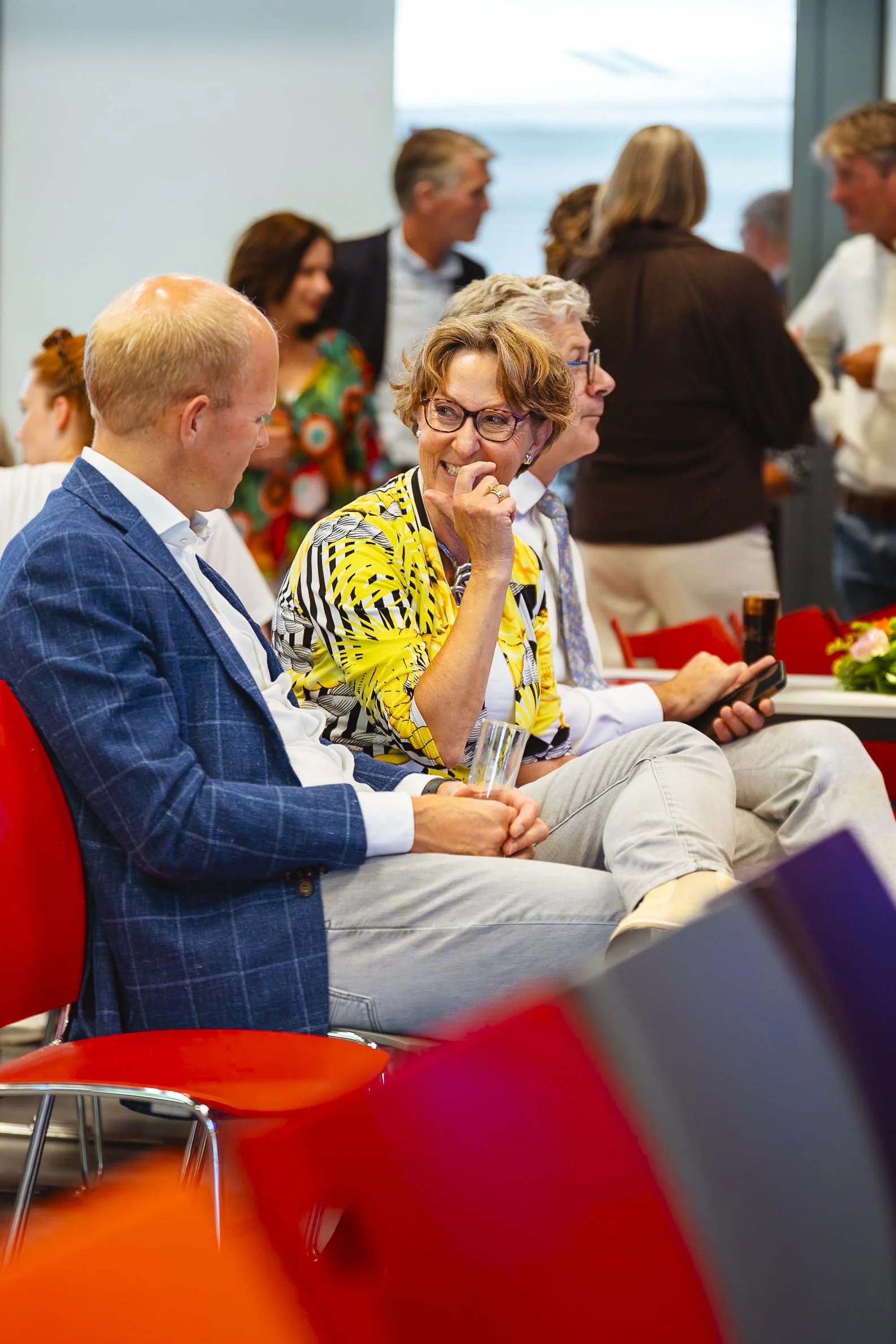 Mensen die in een groep tijdens een bijeenkomst of feest zitten, in gesprek en genieten.