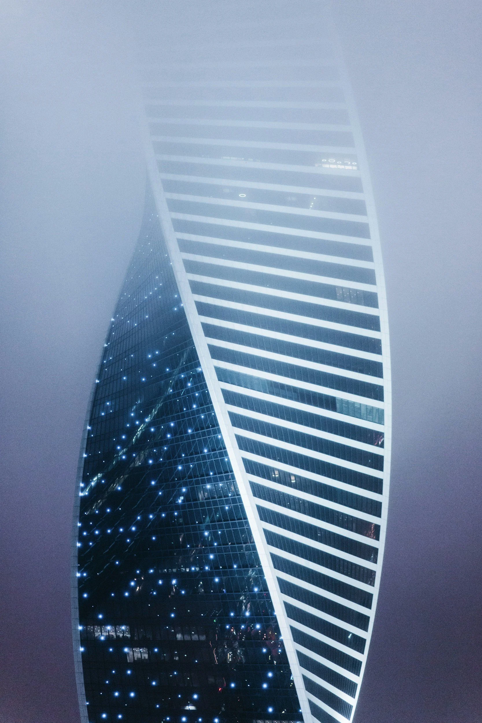 Twisting skyscraper with fog and lights at night