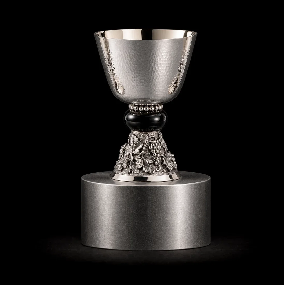  The Vintners Chalice  
 Overall: 22cm&nbsp; Base: 6cm&nbsp; Object: 16cm   
 Hammered silver, black onyx, relief detailing  
 open edition &emsp; Inquire 
