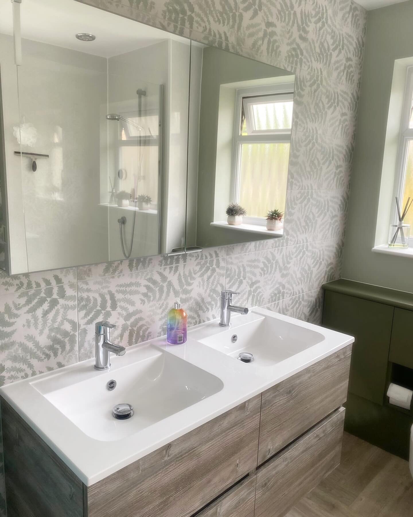 This bathroom was reconfigured to include a large walk in shower and double sinks - the luxurious fern tiles from our National Trust collection create a subtle feature wall that is complimented by the olive green and Bosco wood bathroom furniture . D