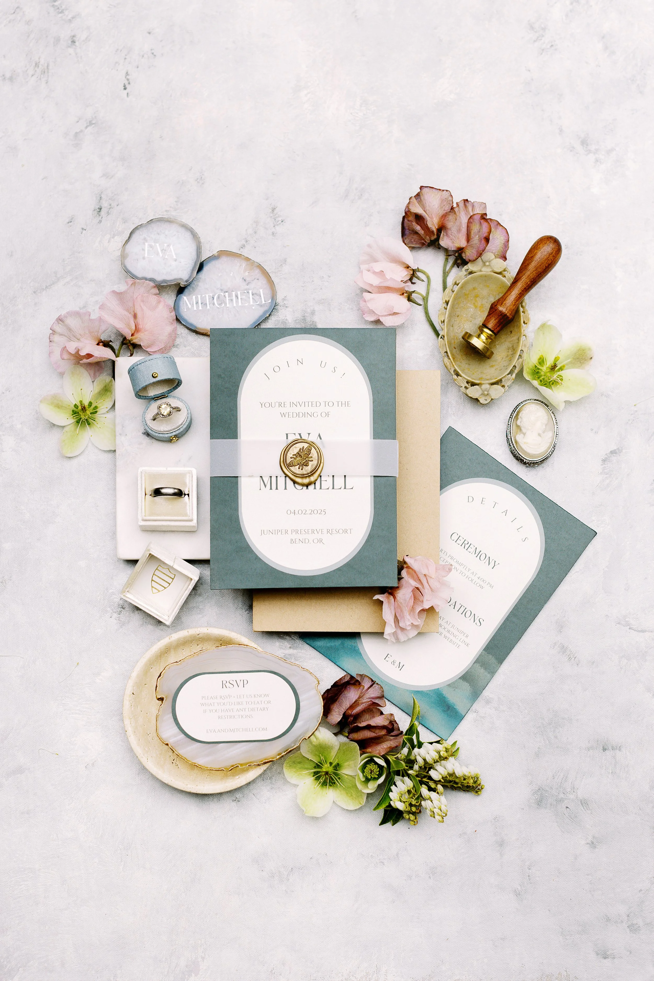 Wedding invitation suite with flowers, rings, and decorative seals on a white background.