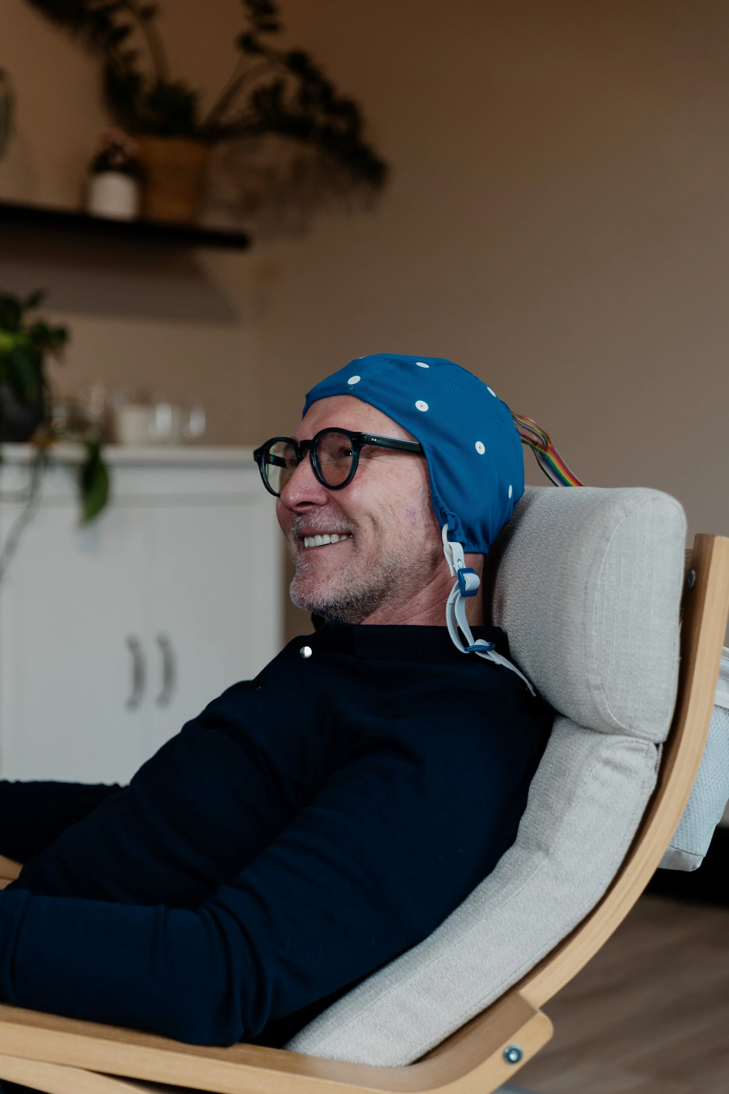 a middle aged man smiling whilst having a QEEG brain map
