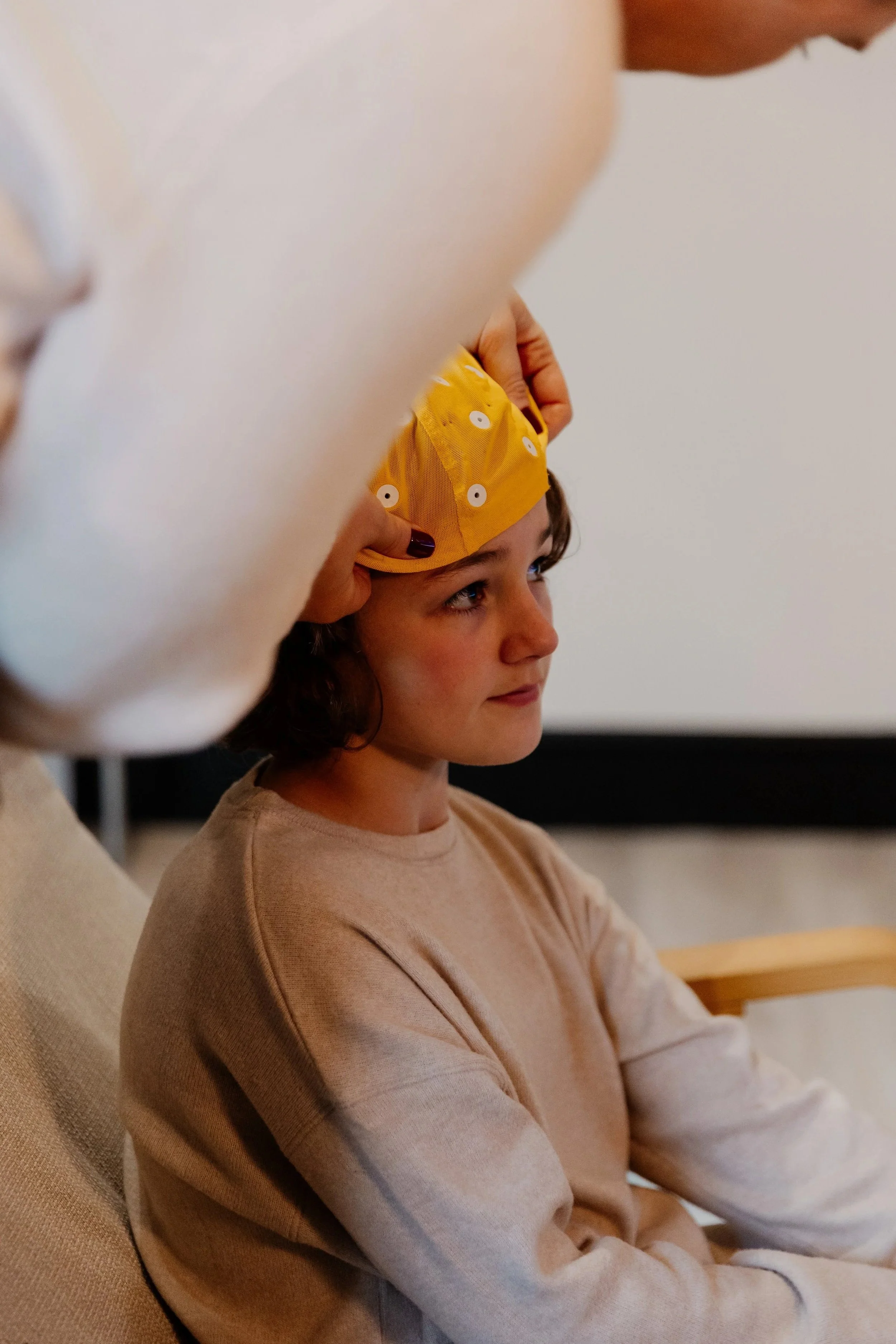 a young girl wearing a yellow QEEG cap
