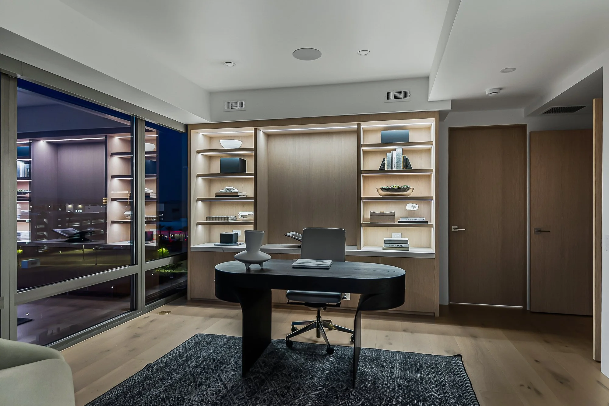Modern home office with integrated shelf lighting and white oak bookcase