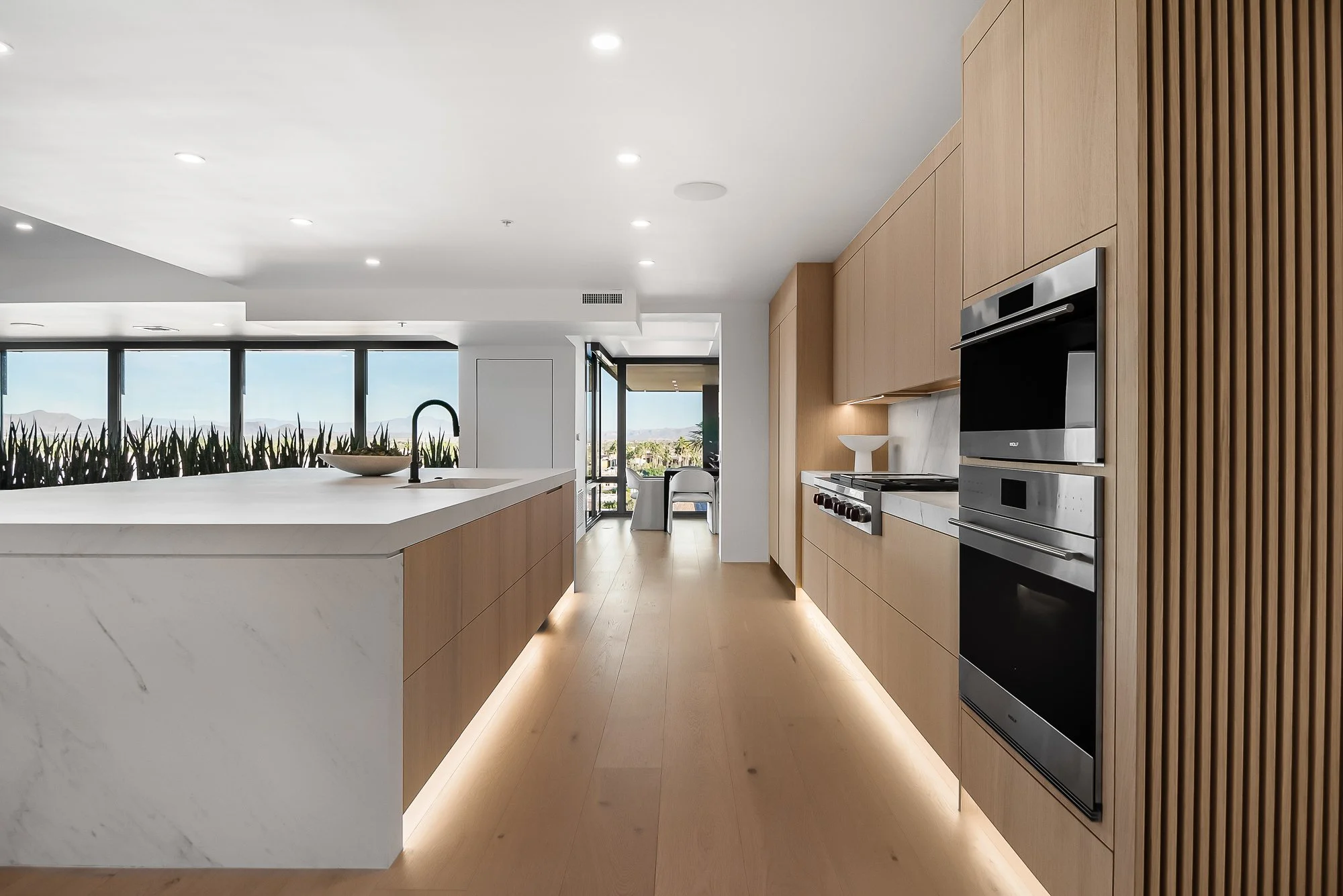 Luxury custom kitchen featuring white oak cabinetry, quartz waterfall island, integrated lighting, and precision architectural millwork.
