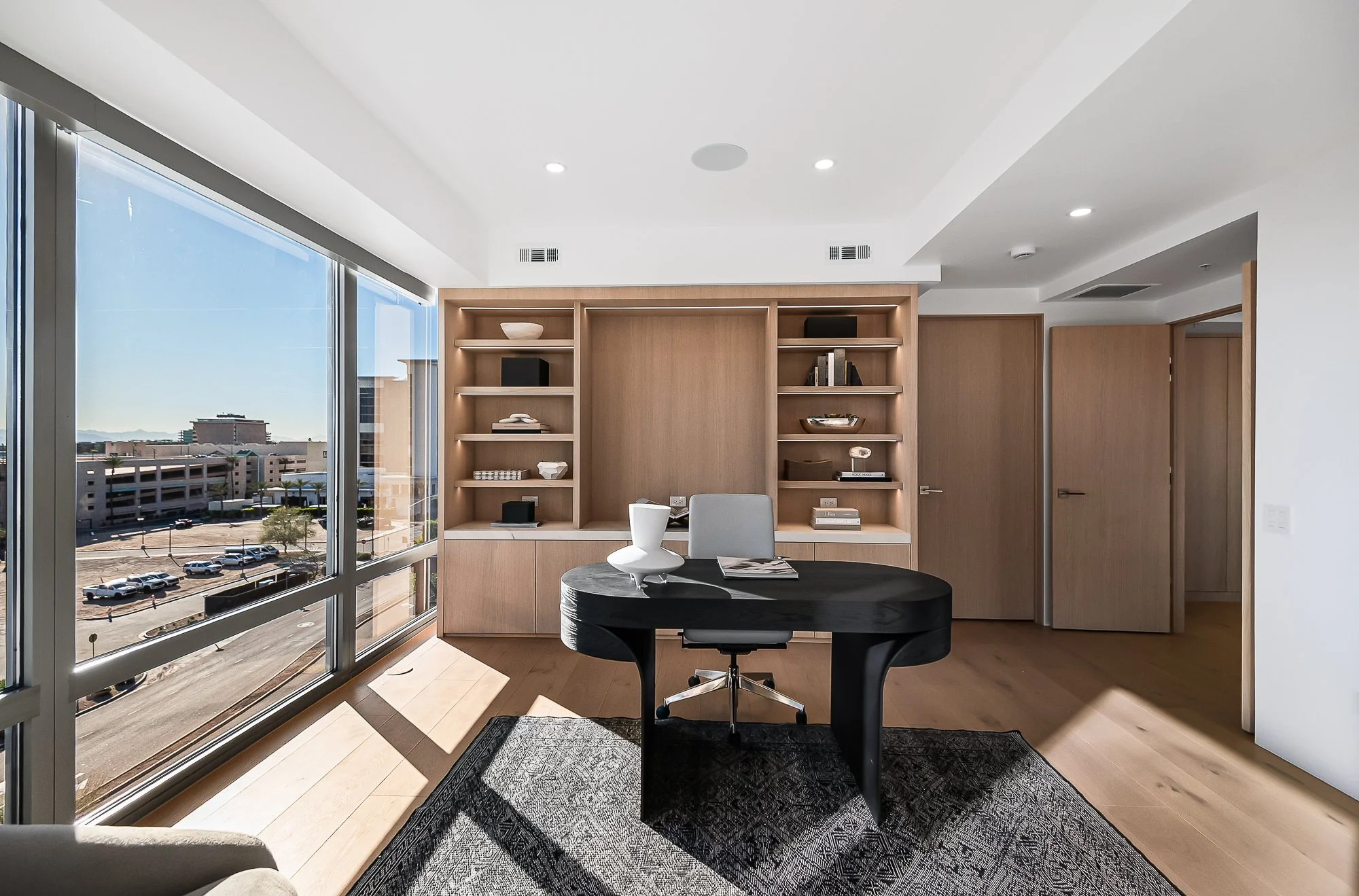 Minimalist white oak home office with black desk and integrated lighting